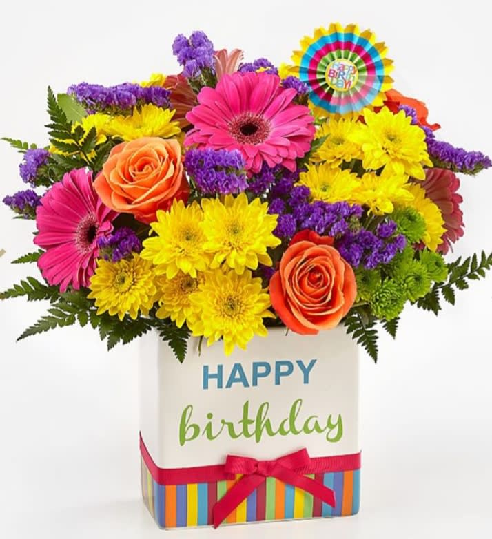 Birthday bright bouquet - The Birthday Brights™ Bouquet is a true celebration of color and life to surprise and delight your special recipient on their big day! Hot pink gerbera daisies and orange roses take center stage surrounded by purple statice, yellow cushion poms, green button poms, and lush greens to create party perfect birthday display. Presented in a modern rectangular ceramic vase with colorful striping at the bottom, &quot;Happy Birthday&quot; lettering at the top, and a bright pink bow at the center, this unforgettable fresh flower arrangement is then accented with a striped happy birthday pick to create a fun and festive gift. BEST bouquet is approx. 14&quot;H x 14&quot;W.