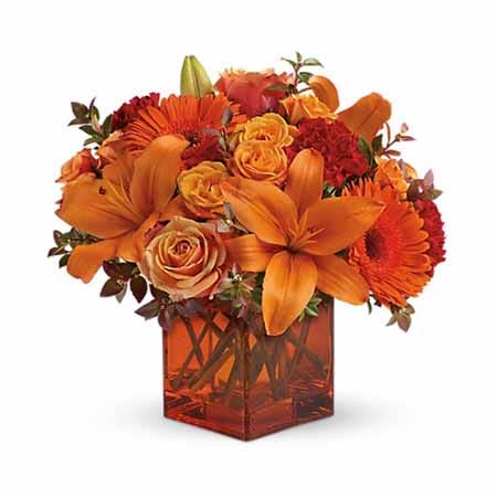 Sunrise Sunset Orange Flower Bouquet - he Sunrise Sunset bouquet celebrates the beauty of every day with gorgeous glowing flowers. Warm orange roses and Gerbera daisies are creatively arranged with red mini carnations and red huckleberry for a soft, glowing presentation. The flowers are presented in an orange cube vase to complete the look, offering stunning beauty at every turn.  Details: • Orange Roses • Orange Gerbera Daisies • Red Mini Carnations • Red Huckleberry • Orange Glass Vase