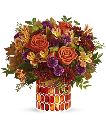 Teleflora's Autumn Radiance Bouquet - Radiant roses and lush fall blooms are presented to perfection in a keepsake mosaic vase of stunning stained glass. This radiant arrangement includes orange roses, light orange alstroemeria, purple button spray chrysanthemums, burgundy cushion spray chrysanthemums, bupleurum, seeded eucalyptus and huckleberry, accented with transparent oak leaves. Delivered in Teleflora's Autumn Radiance Mosaic vase. Orientation: All-Around
