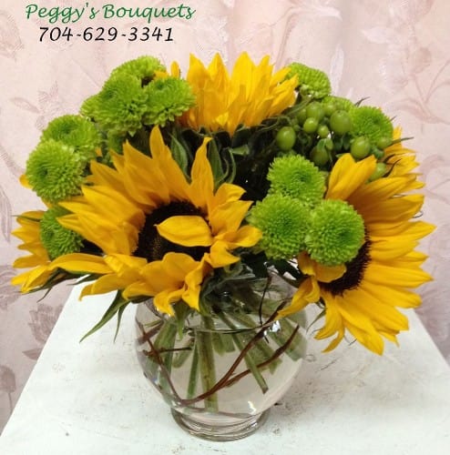 Cup O Sunshine - Beautiful sunflowers with hypericum berries and green buttons held in place with curly willow. Beautiful for any occasion or just because. Upgrade to $50 and add roses for that special touch.
