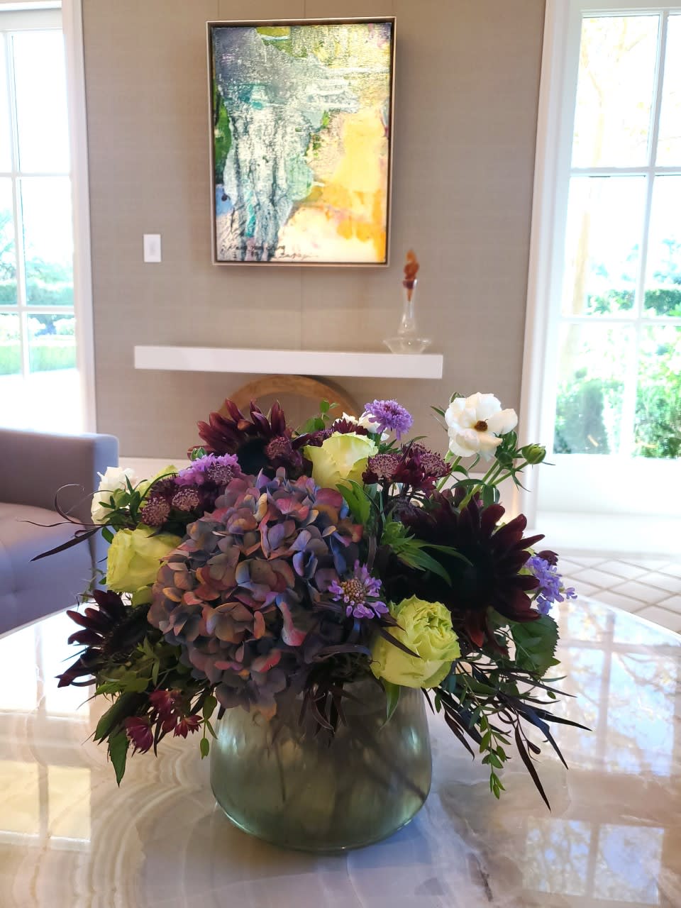Painted Chocolate Painted Chocolate - A timeless arrangement with hues of purple, lime green, deep chocolate, and a pop of white. Hydrangea, roses, scabiosa and chocolate sunflowersin a modern vase from the Amelia Collection. Chocolate sunflowers may be substitutes for burgundy dahlias and chocolate cosmos