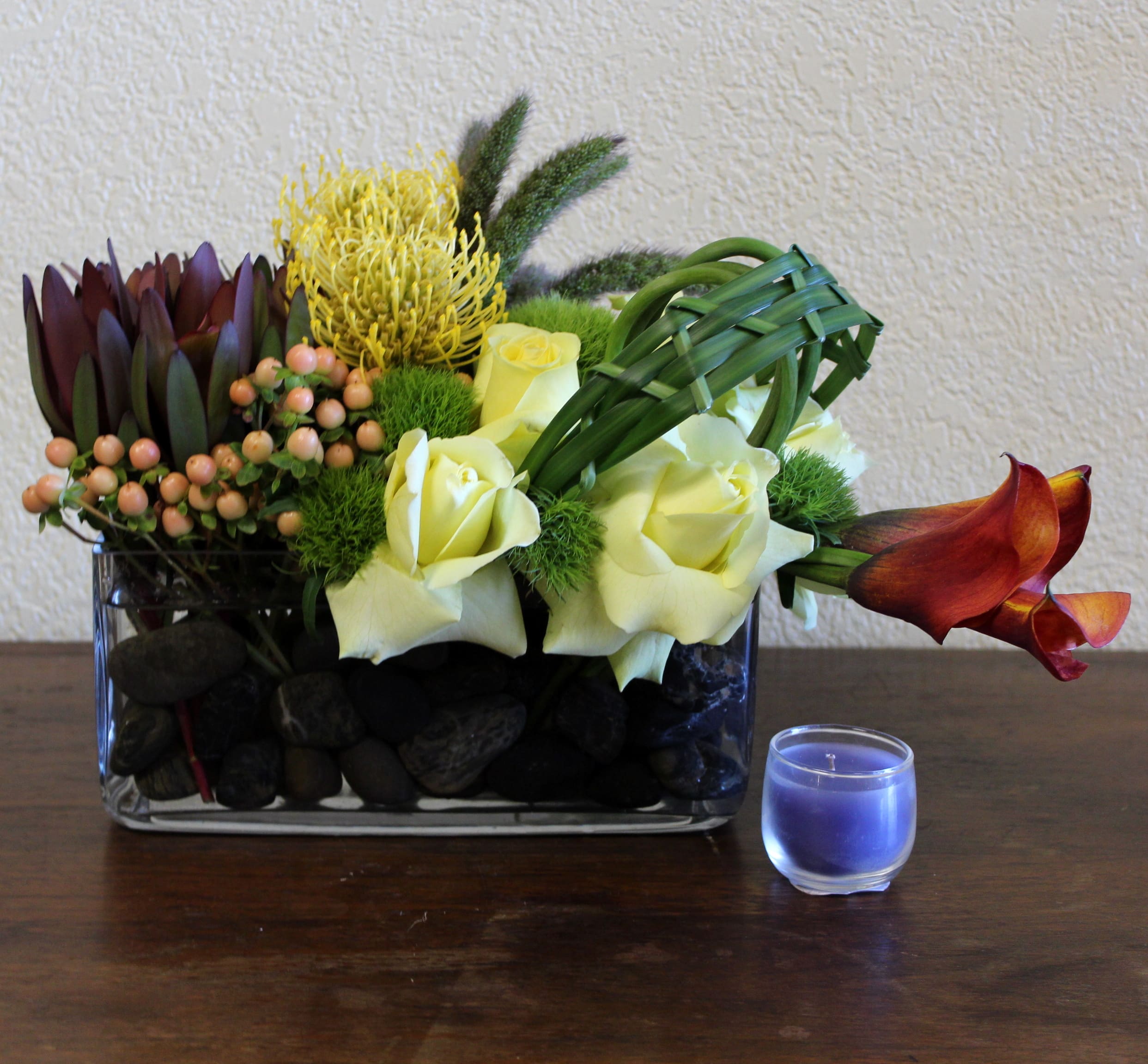 River Stone - Sunset colored callas, roses, and vibrant pin protea