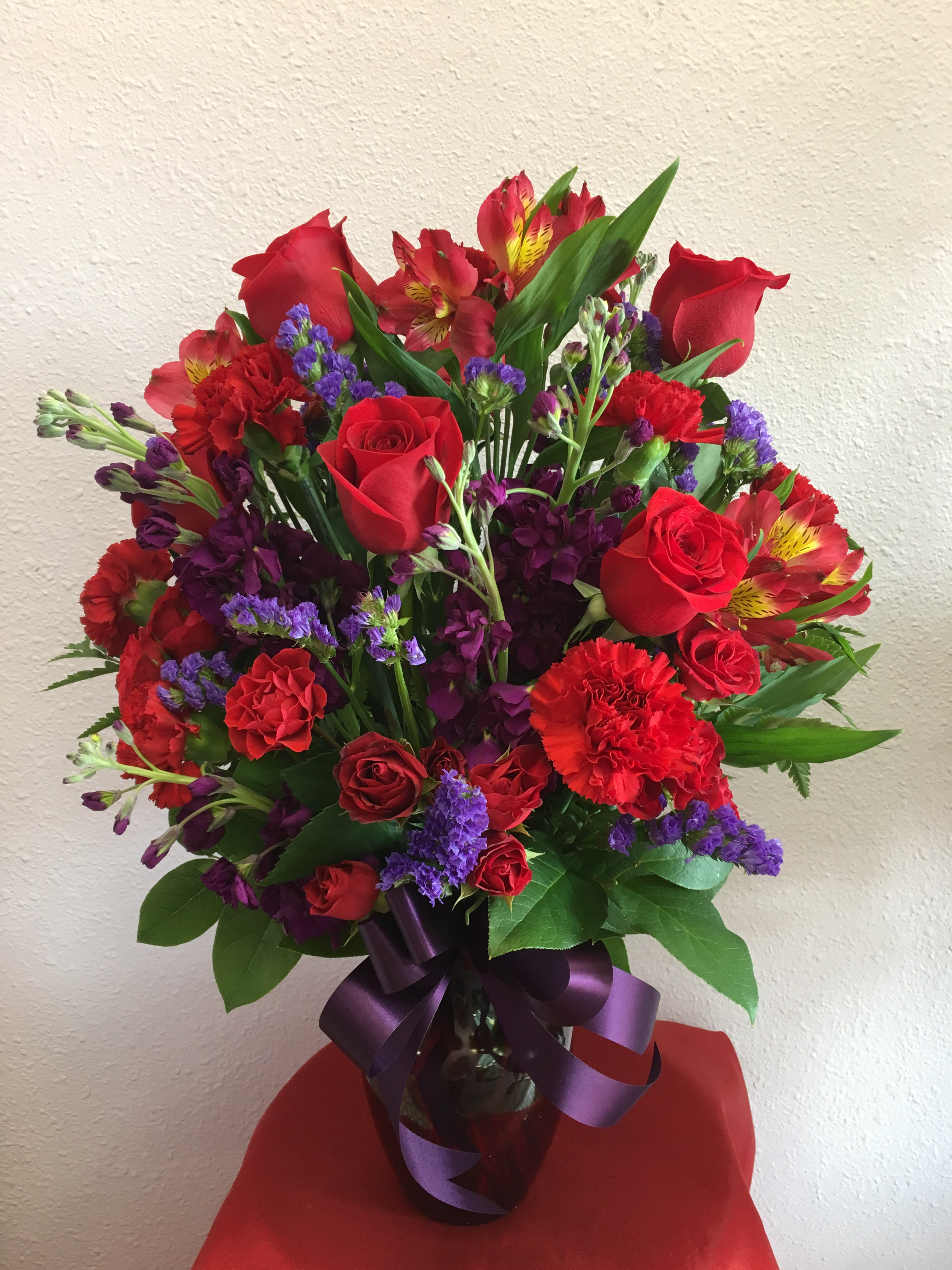 Royal Reds By Forever Flowers - Red Roses, Spray Roses, purple Stock, and pink Alstroemeria with purple accents.