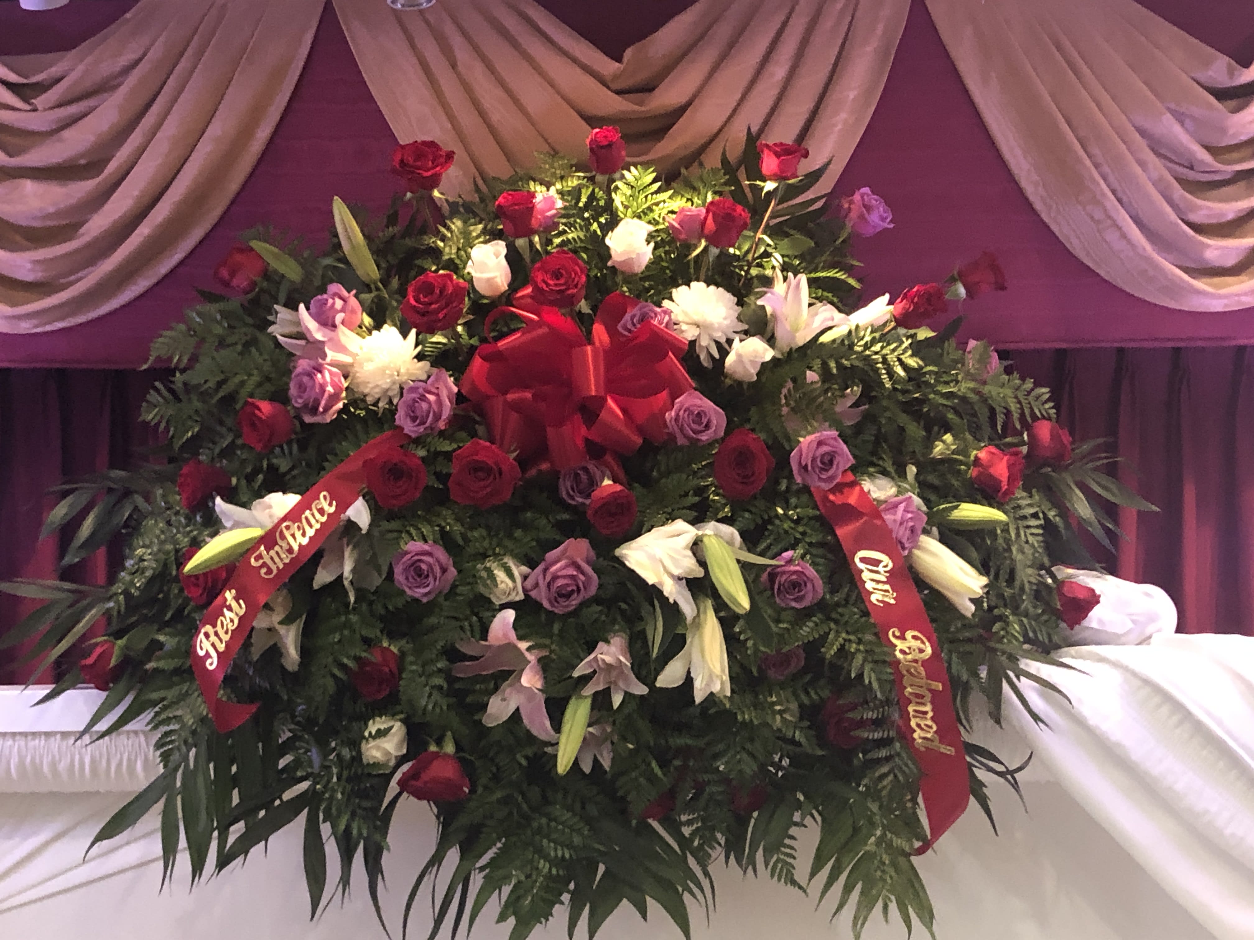 Large floral spray of red, pink, purple, and white flowers with ribbons