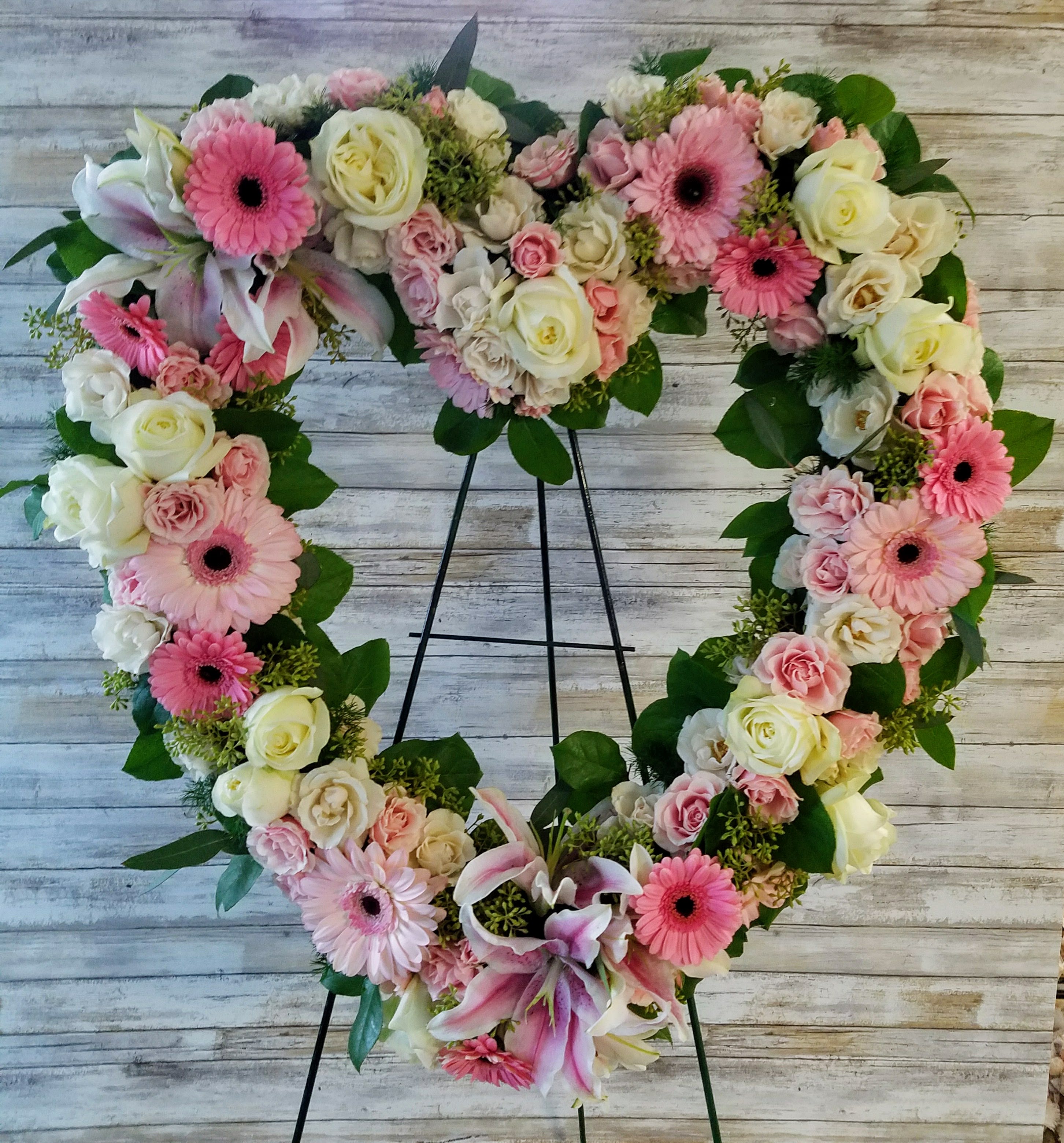 Pink & White Heart Tribute Pink & White Heart Tribute - In the shape of a heart, and accented with a pink satin ribbon, this garden of delicate blooms is a tender and classic tribute to a precious life, and a cherished expression of love and sympathy.  Including roses, spray roses, lilies, gerbera daisies accented with eucalyptus and lemon leaf.   22"