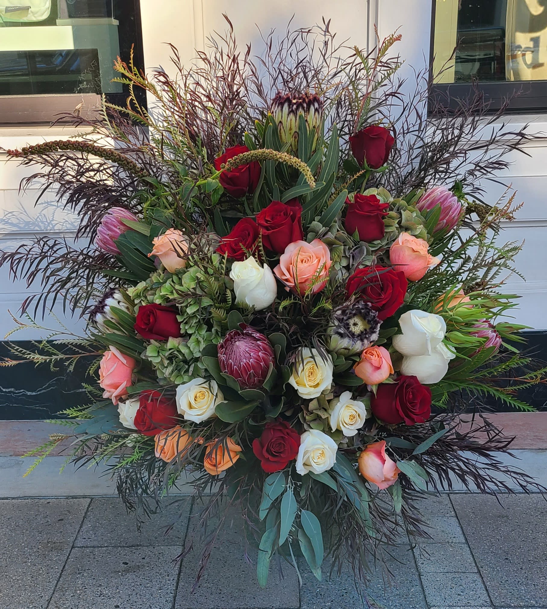 Protea floor spray - This floor spray stands approximately 3’ in height and is arranged in a one sided fashion. Please note the foliage may vary depending on the season.