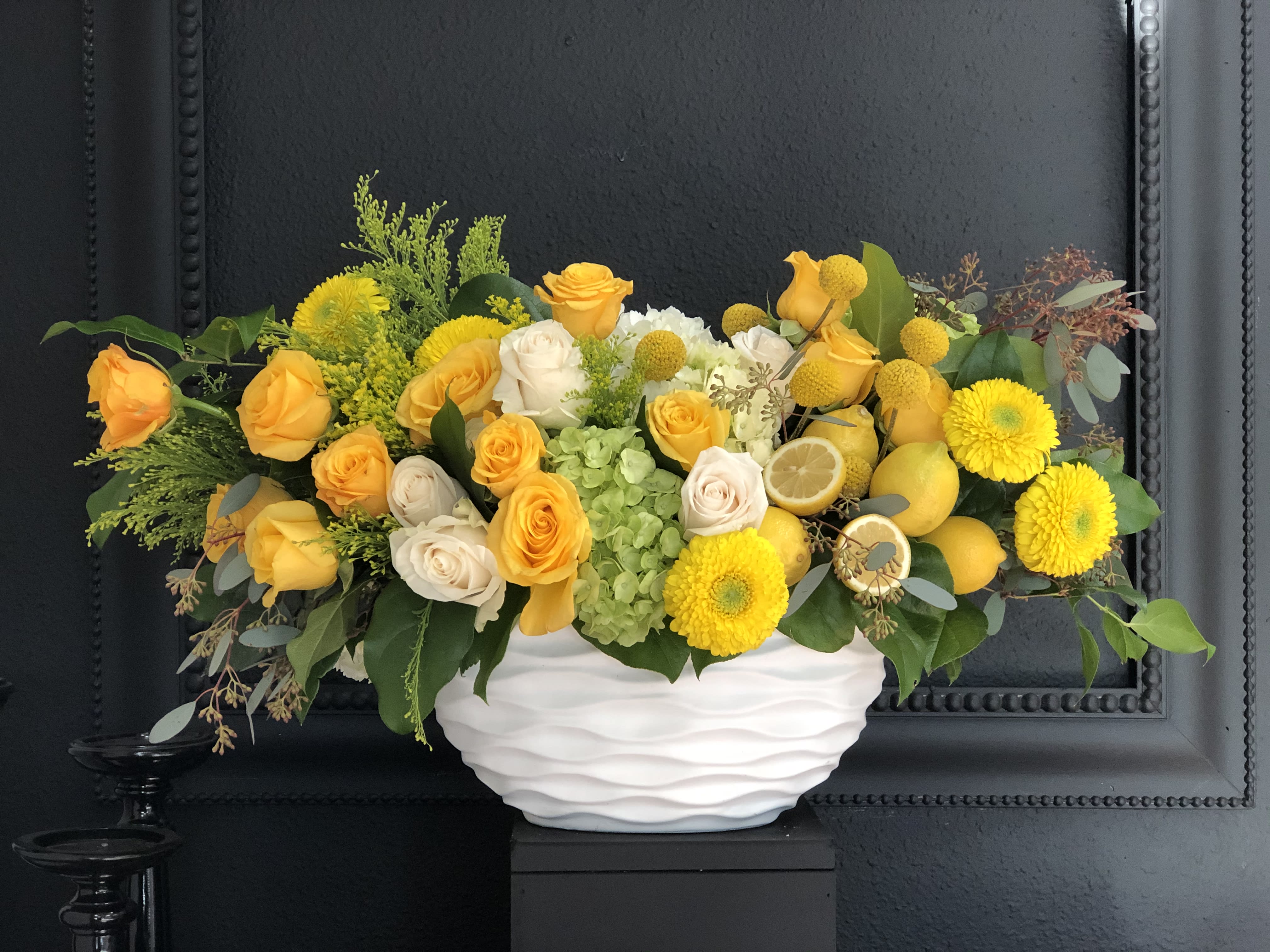 Lemons - Yellow and green arrangement in white vase. Lemons are added for fresh look and style. This arrangement will put a smile on recipients face upon delivery.