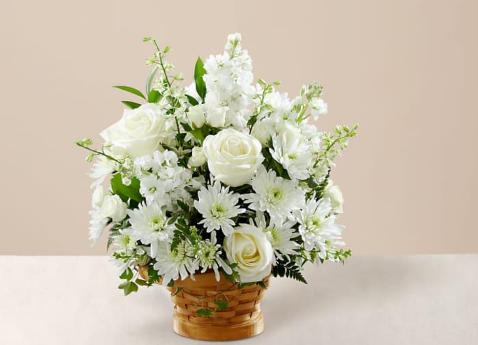 Heartfelt  - Let this exquisite composition of beautiful white blossoms deliver your sympathy and comfort loved ones grieving a loss. The elegance of this arrangement and its warm, homey basket base makes it an appropriate addition to any wake, funeral or graveside service, or to send to the home of family or friends. Handcrafted by a local artisan florist of individually selected white roses, stock, cushion pompons and larkspur set among complementary greens for a memorable bouquet that evokes a tranquil sense of heavenly hope.