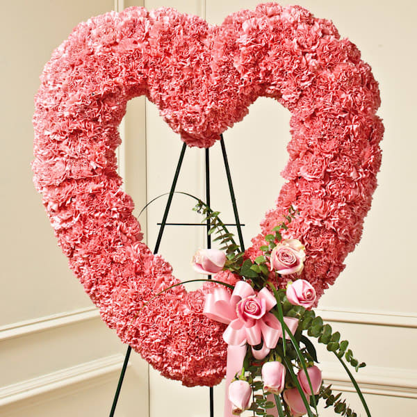 Pink Standing Open Hear - When you need a beautiful way to convey your sympathy and love, this open heart standing spray is the perfect choice.  • Crafted of soft pink roses and carnations, accented by bear grass • Sent directly to the funeral home by family and friends • Measures approximately 26&quot;H x 26&quot;W without easel