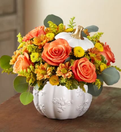 Plentiful Pumpkin - A plentiful mix of blooms gives our autumn arrangement an undeniable charm. Loosely gathered with traditional pops of red, orange and yellow, it’s the perfect contrast to our modern-styled pumpkin. Featuring a white satin finish, embossed detail and rich golden accents, this harvest-inspired container is an ideal pick for fresh flowers, wrapped candies or as a cozy seasonal accent.