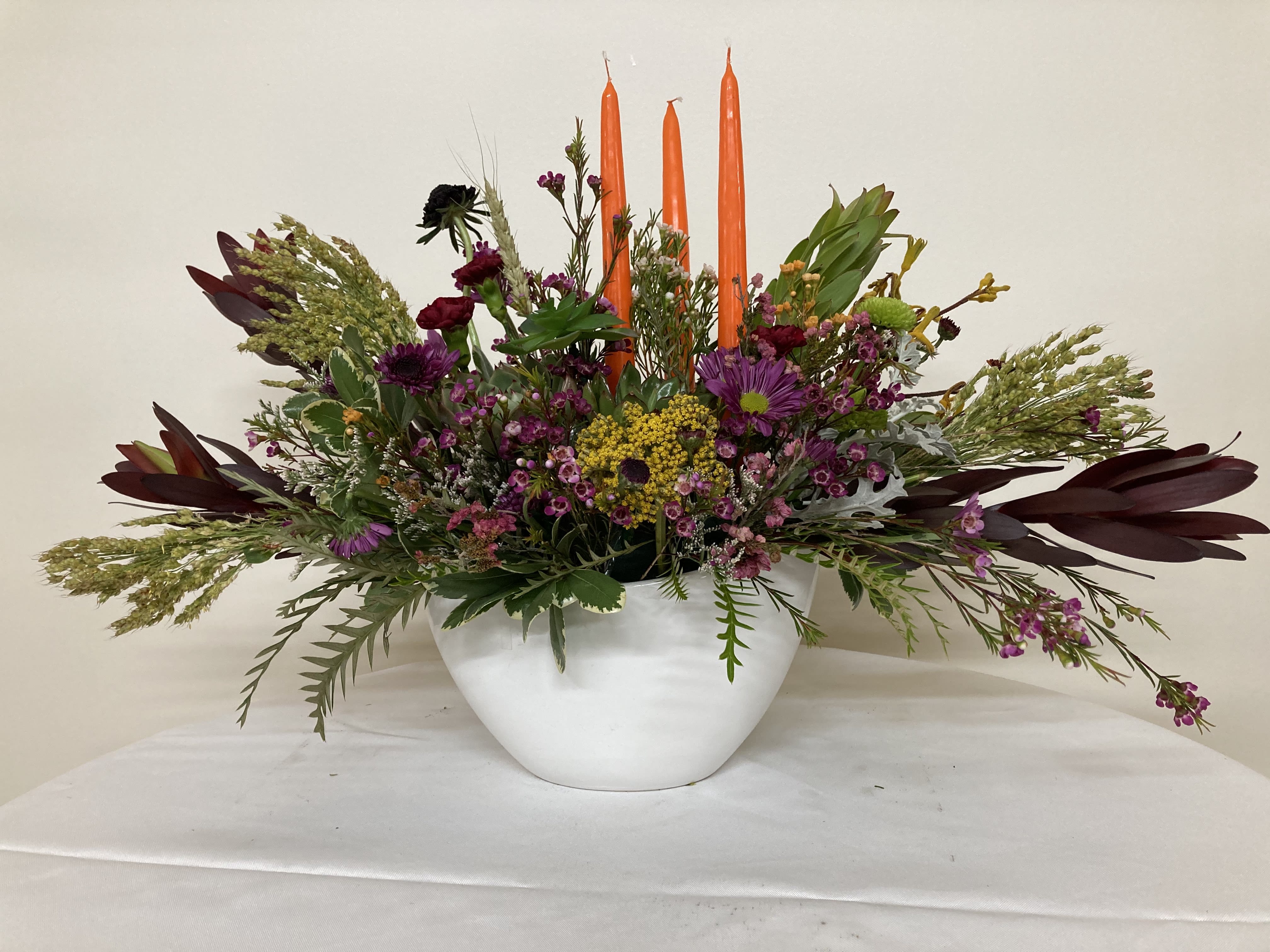 Autumn Mist - Three tapered candles rise above succulents, daisies, and the colorful flowers of autumn.