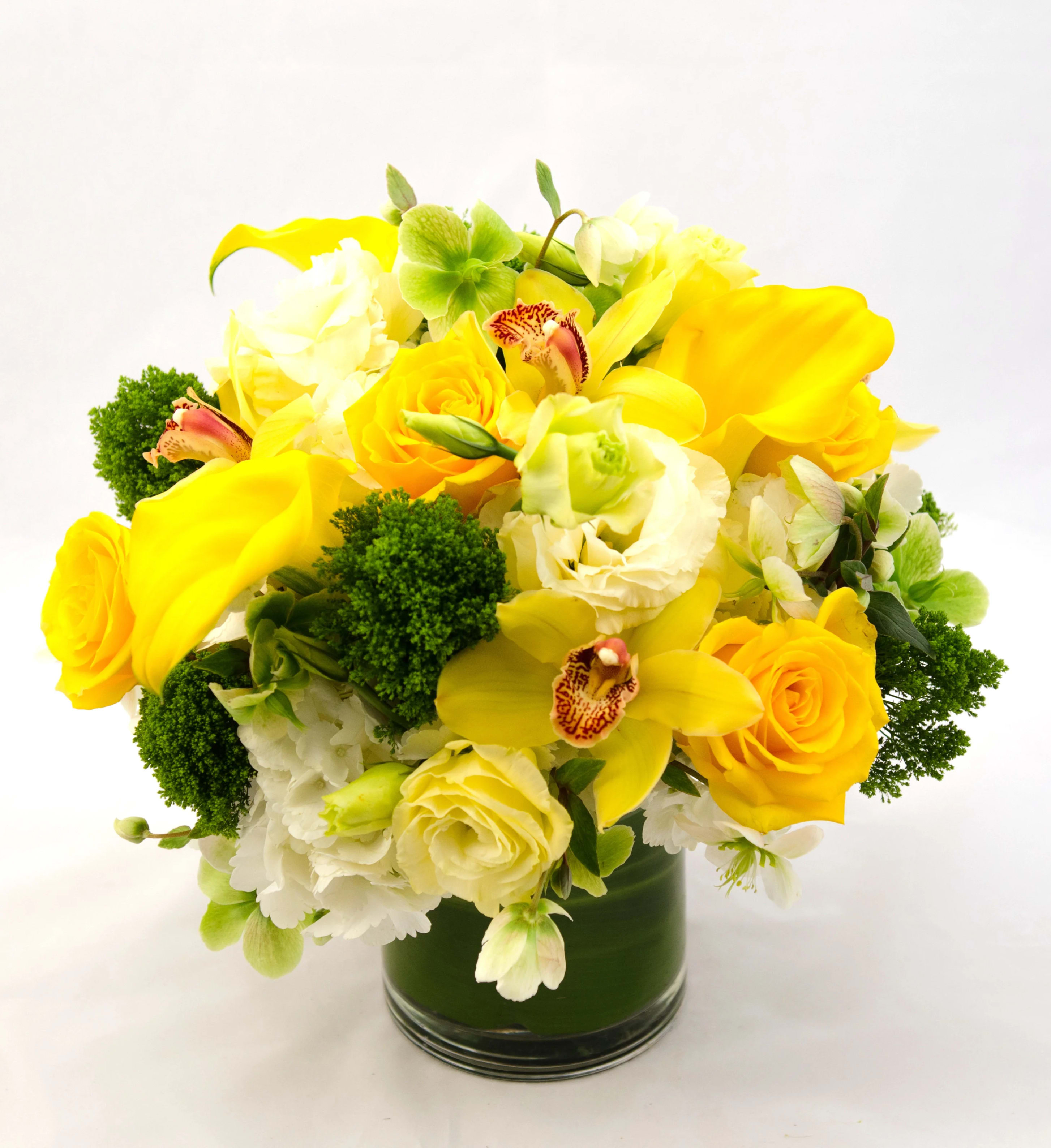 Unique Ways - Scrumptious South American hydrangea, classic Lemon roses, green dianthus and market fresh seasonal accents in a glass container with a leaf wrap to hide the stems.    Approximately 10&quot; tall.   
