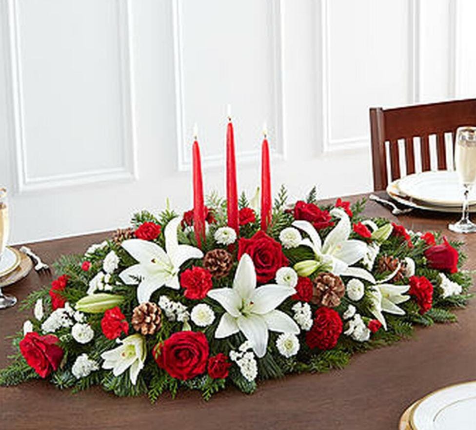 Classic Christmas Centerpiece Premium - Our traditional table arrangement creates the perfect centerpiece for your Christmas celebration. Beautifully designed with long-lasting blooms in seasonal colors, this fragrant gathering features red taper candles to cast a warm, cozy glow throughout the holidays.