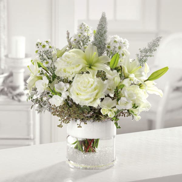Silent Night - Snowy white roses, lilies, freesia and mixed greens come together in a glass cylinder vase to bring a sense calm amid the holiday hustle and bustle.