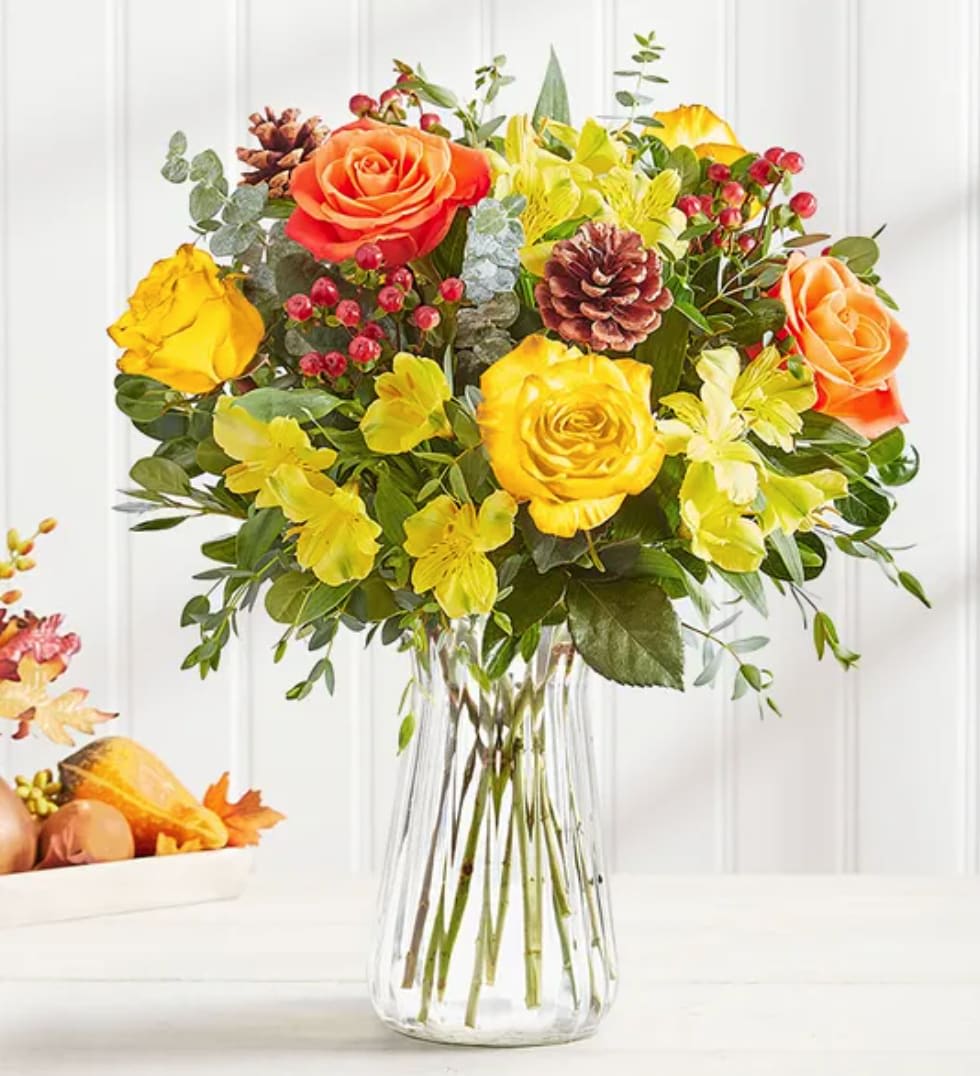 Country Harvest - Our vibrant new bouquet captures the beauty and charm of a country harvest. Orange roses and yellow lilies set the tone for fall against textured berry and pinecone accents. Lush pops of greenery fill out this rustic gathering—the perfect gift for a season of coming together.  