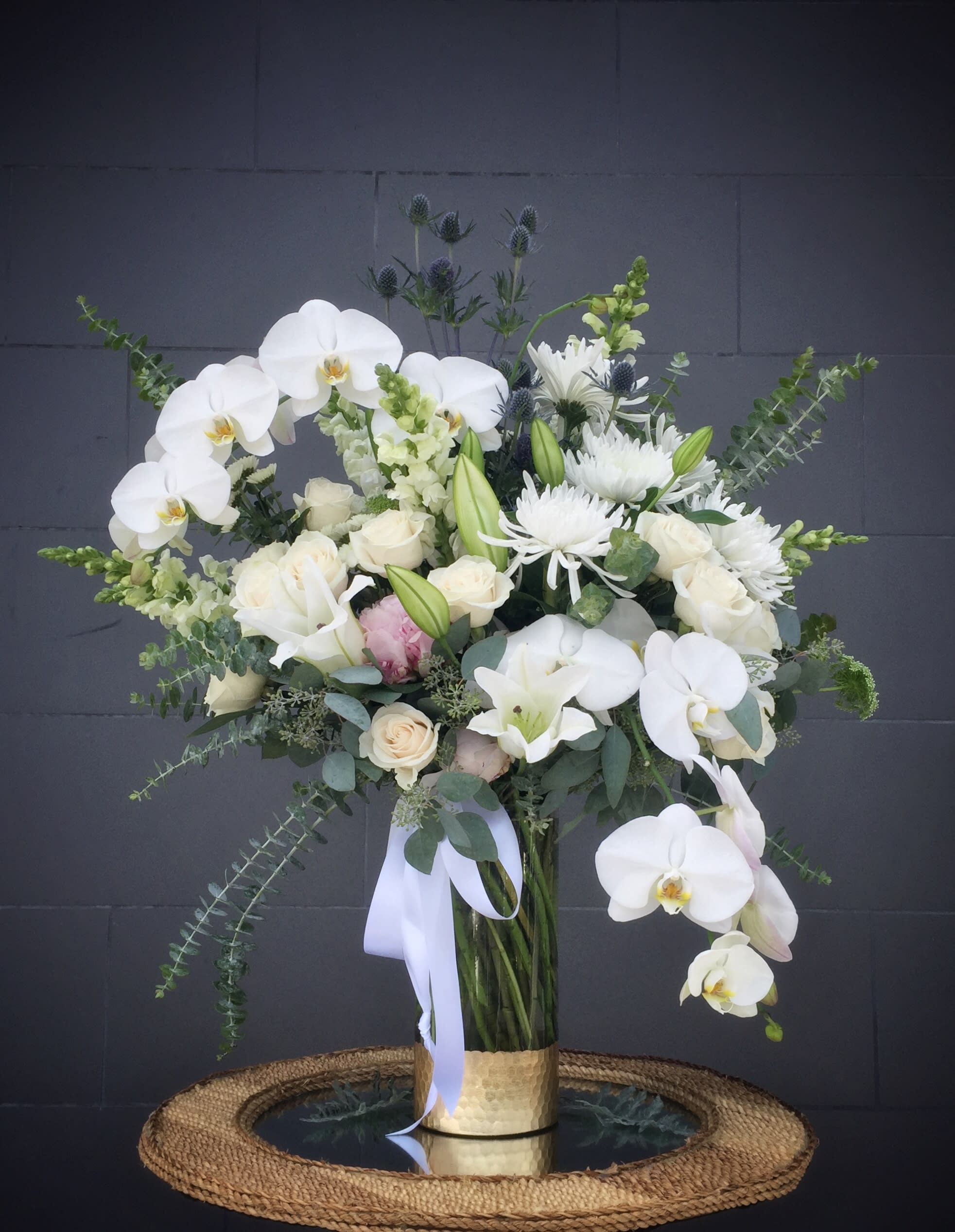 White Wow - Elegant white including all premium flowers and accents in a tall glass vase. STANDARD: FIRST PHOTO DELUXE: SECOND PHOTO