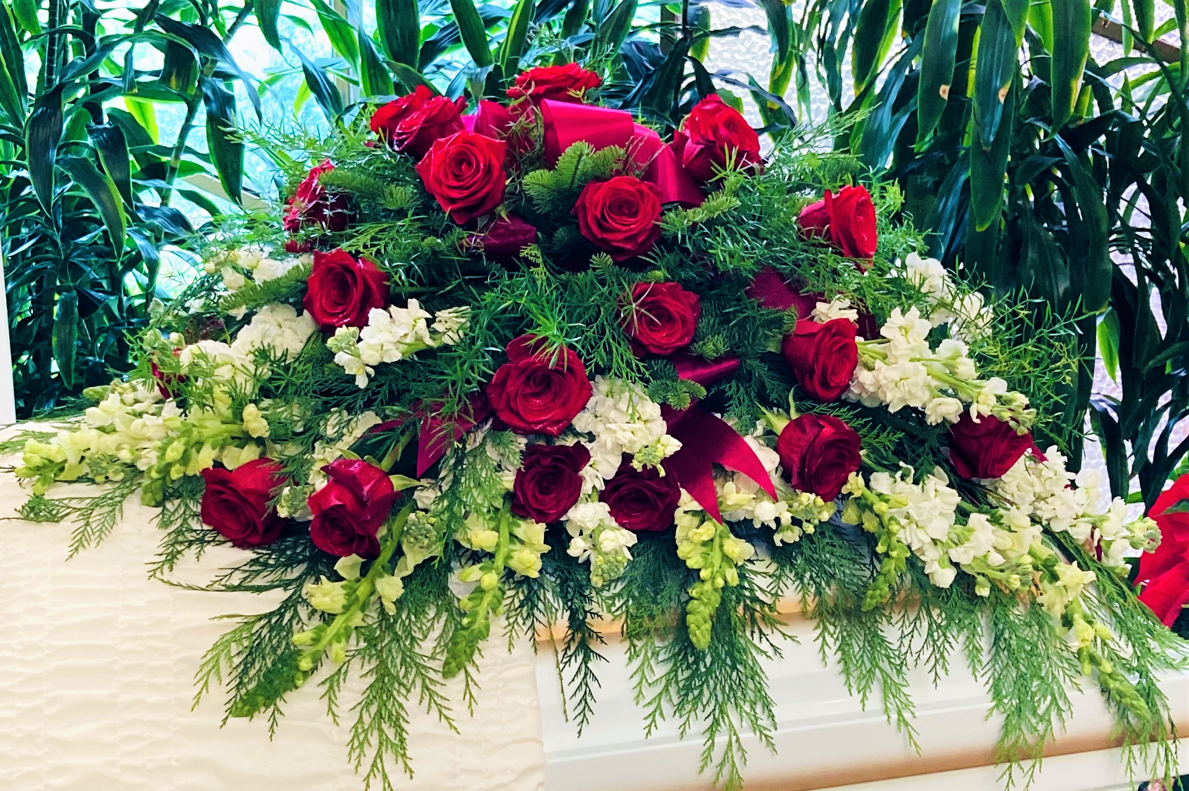 Winter Casket Spray Winter Casket Spray - This spray is composed of over 3 dozen beautiful Red Roses, outlined in luscious blooms of White Stock, and White Snapdragon. The spray is filled with various foliage including Flat Cedar, Noble Fir, and Sprengeri Fern. Approx. dimensions are 36"L x 26"W x 12"H. ***Please note that Cedar and Noble Fir will be substituted with other foliage options during Spring and Summer seasons. Please inquire within.