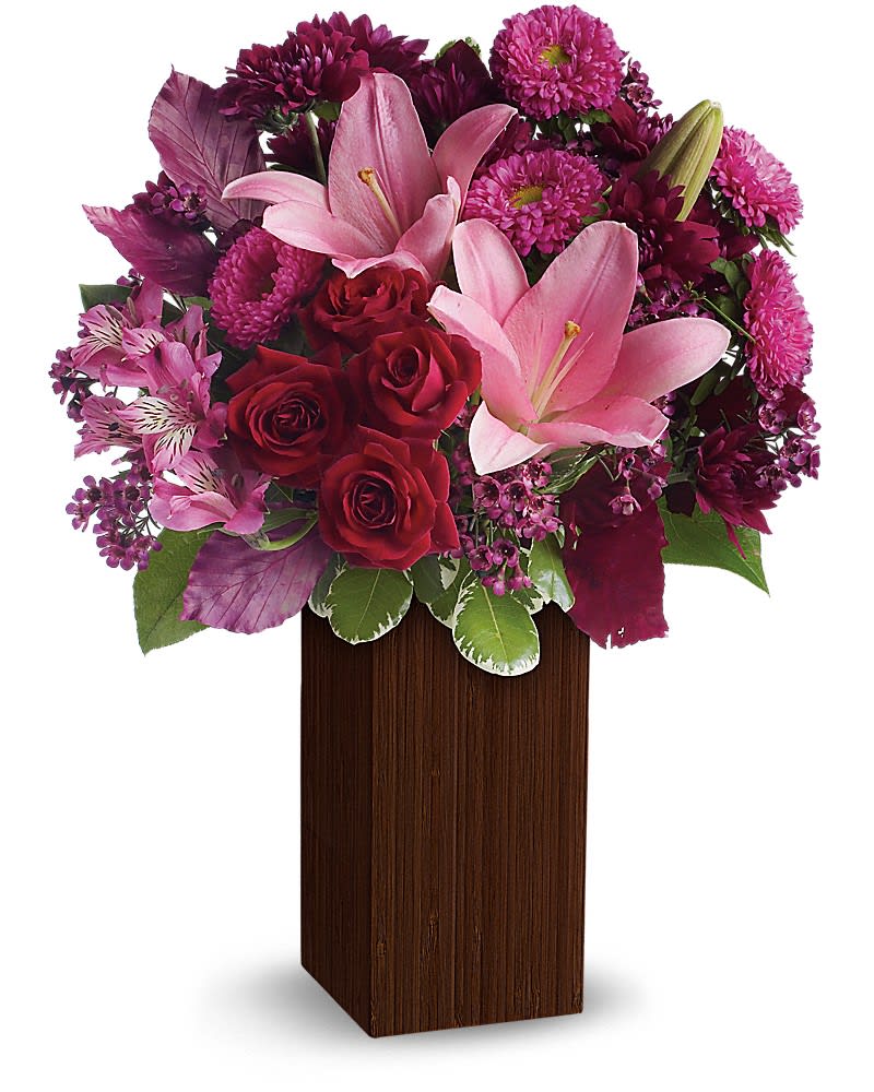 A Fine Romance by Teleflora - Dazzle and delight her with this magical mix of soft lavenders, rich reds and playful pinks. The fine, feminine blooms speak to your feelings, while the sleek bamboo container speaks to your style. Dark red roses, pink asiatic lilies, purple alstroemeria, hot pink matsumoto asters, purple chrysanthemums and lavender waxflower are accented with burgundy copper beech and variegated pittosporum. Delivered in a tall bamboo vase in a rich shade of brown that anchors the arrangement in modern style.