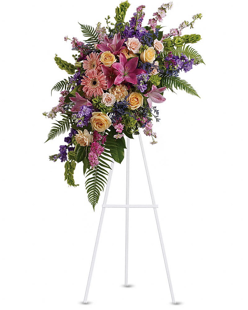 Heavenly Grace Spray Heavenly Grace Spray - A sublime garden of rich yet subtle hues is a touching tribute to a lifetime of memories and special moments as varied and dear as this palette of blooms. A lovely assortment of flowers such as pink roses, larkspur, asiatic lilies, gerberas and sinuata statice, with peach roses and carnations, purple stock and limonium, and bells of Ireland on a classic easel.