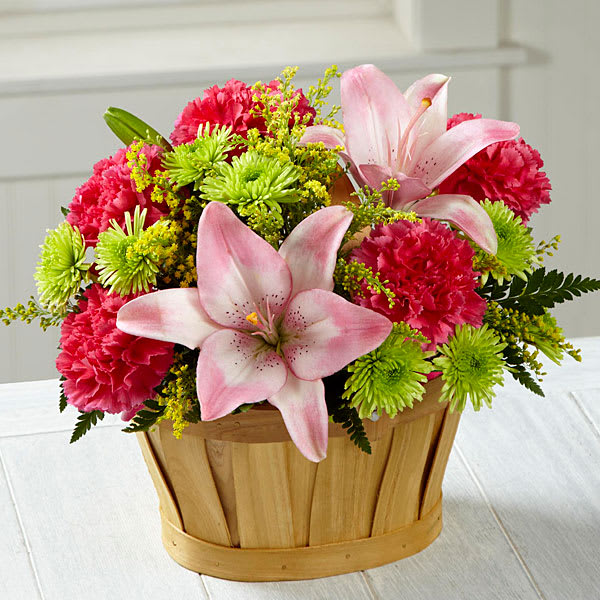Soft Persuasion Bouquet - Blossoming with a blushing grace and casual appeal your recipient will adore this fresh flower arrangement will persuade them to see the beauty of all that surrounds them. Pink Asiatic Lilies are the star of this bouquet surrounded by hot pink carnations, yellow solidago green button poms and lush greens arranged to perfection in an oval woodchip basket to give it a chic country garden styling. A lovely way to say thank you get well or congratulations!