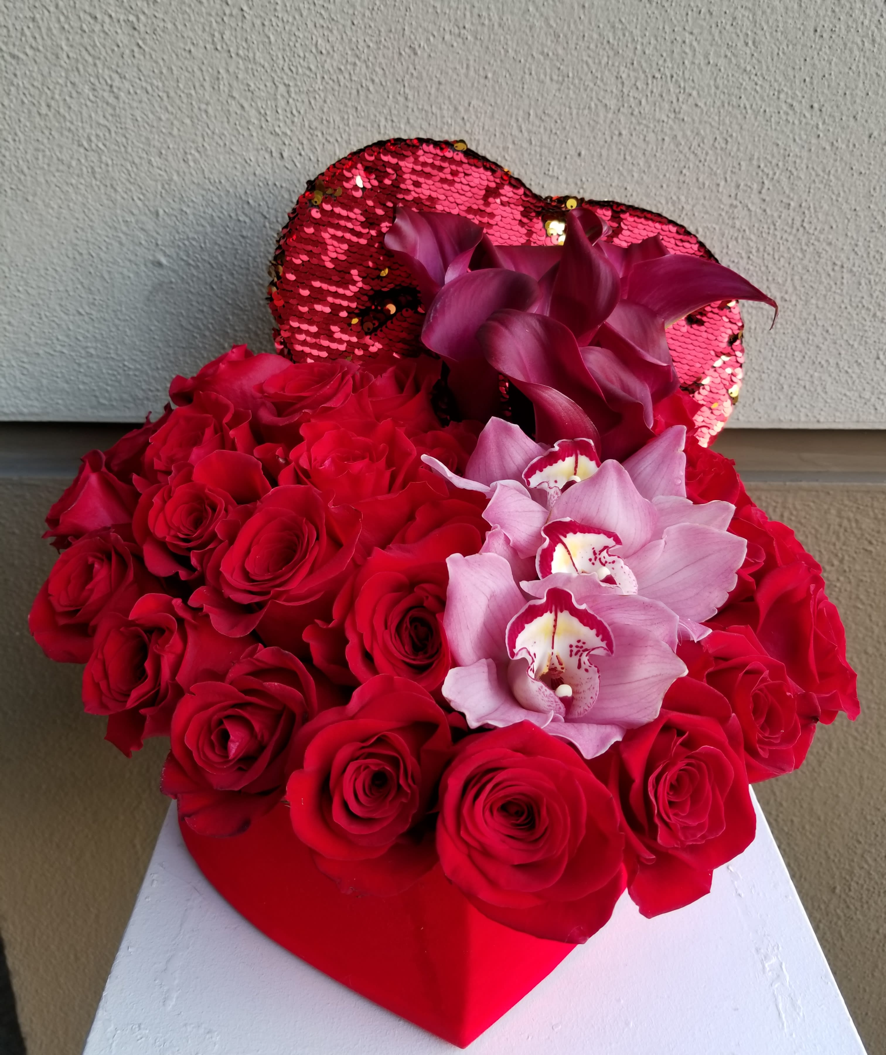 Red Heart - Red roses, pink orchids and red mini calla lilies designed in a red heart.