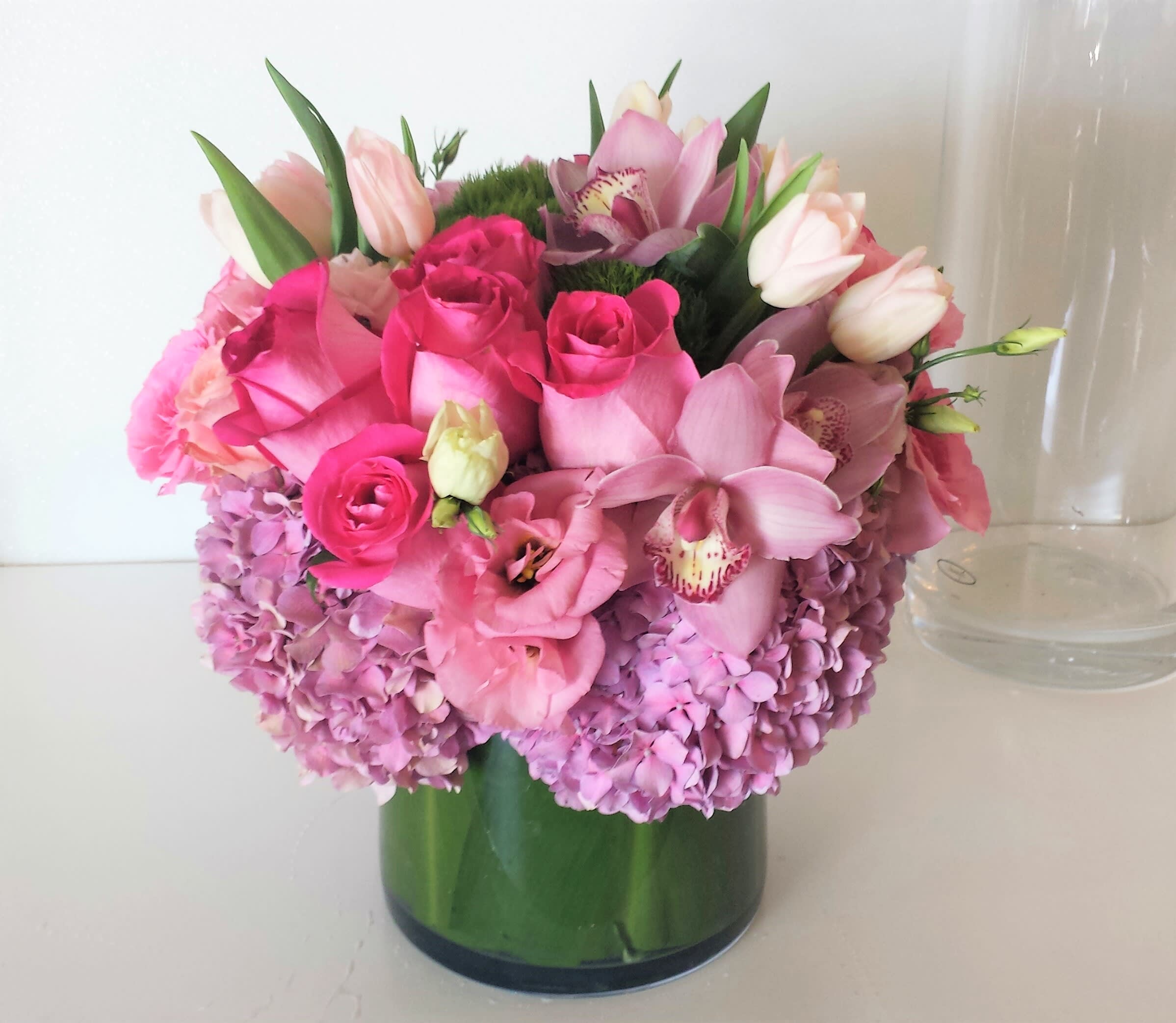 Popular Pinks - Beautiful display of all pinks popular blooms like hydrangeas, roses, tulips and orchids.  This design is all around in a low cylinder vase.