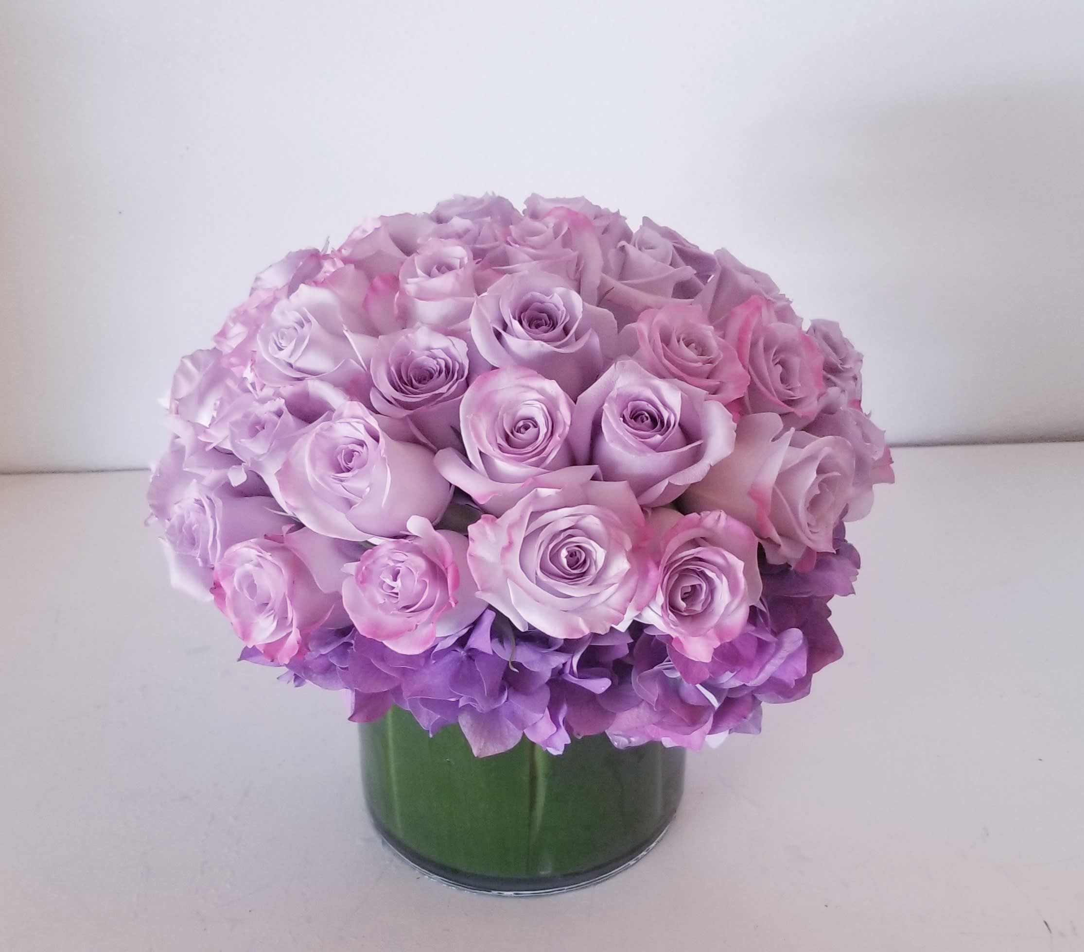Lavender Affection - Low glass cylinder composed of lush lavender roses.