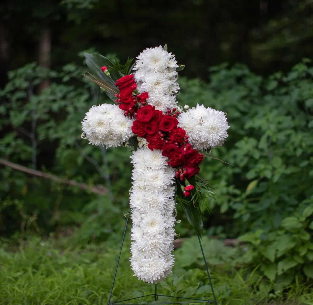 Devotion Hanging Cross Spray - Traditional solid white cross base with an elegant spray of red roses. Designed for funeral directors to place on an easel during services. Other colors are available. Same day delivery may not always be possible as a significant amount of white flowers are required to create the look. 