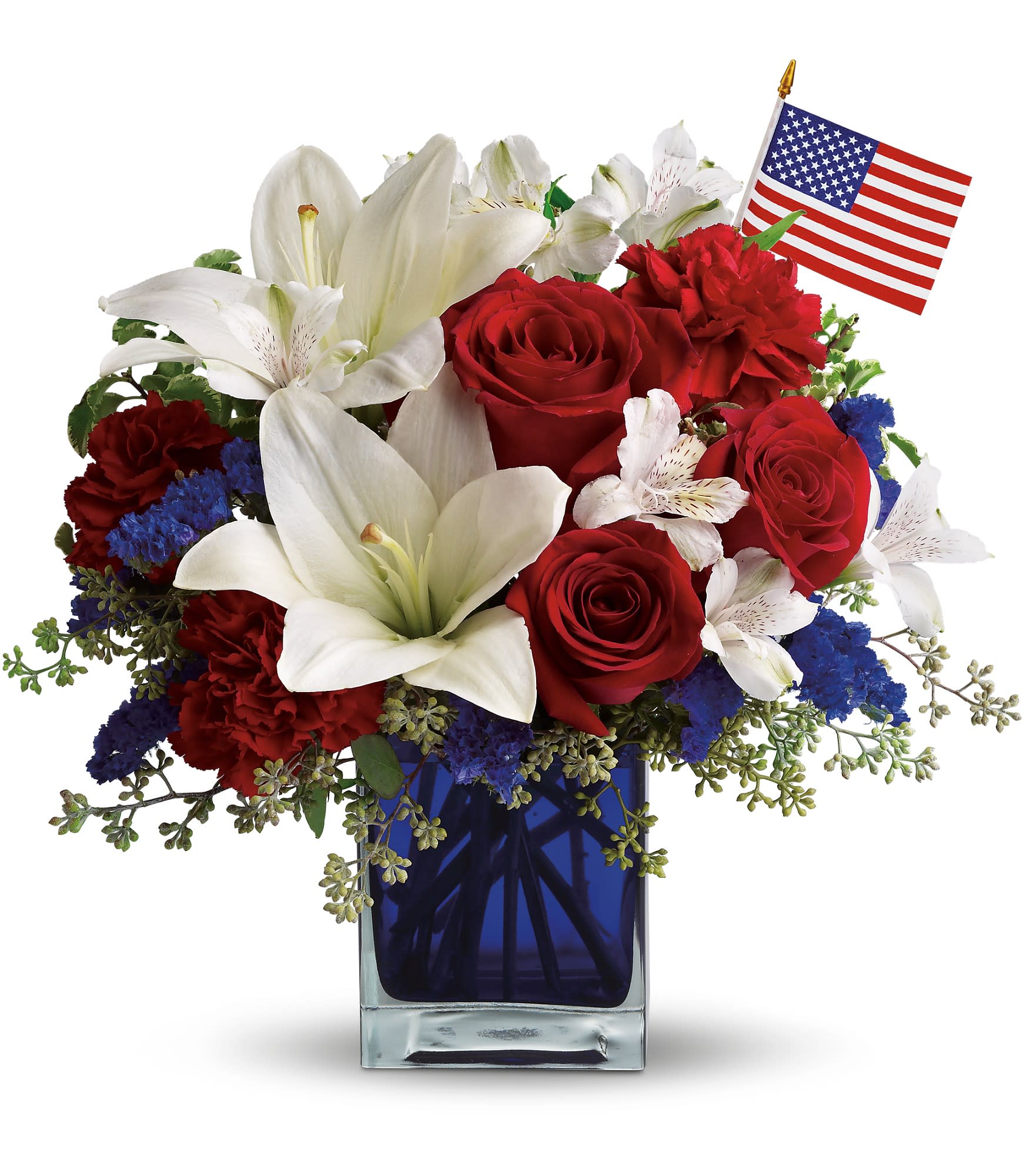 America the Beautiful  - This patriotic arrangement is such a stunning way to honor the courage, the character, the people and the places in this country we call home. It is a SMALL table top design. Also available in a taller blue vase- call for details.  Can be done in a clear cube or other shape blue vase. Lilies are TOXIC to cats- we can substitute!