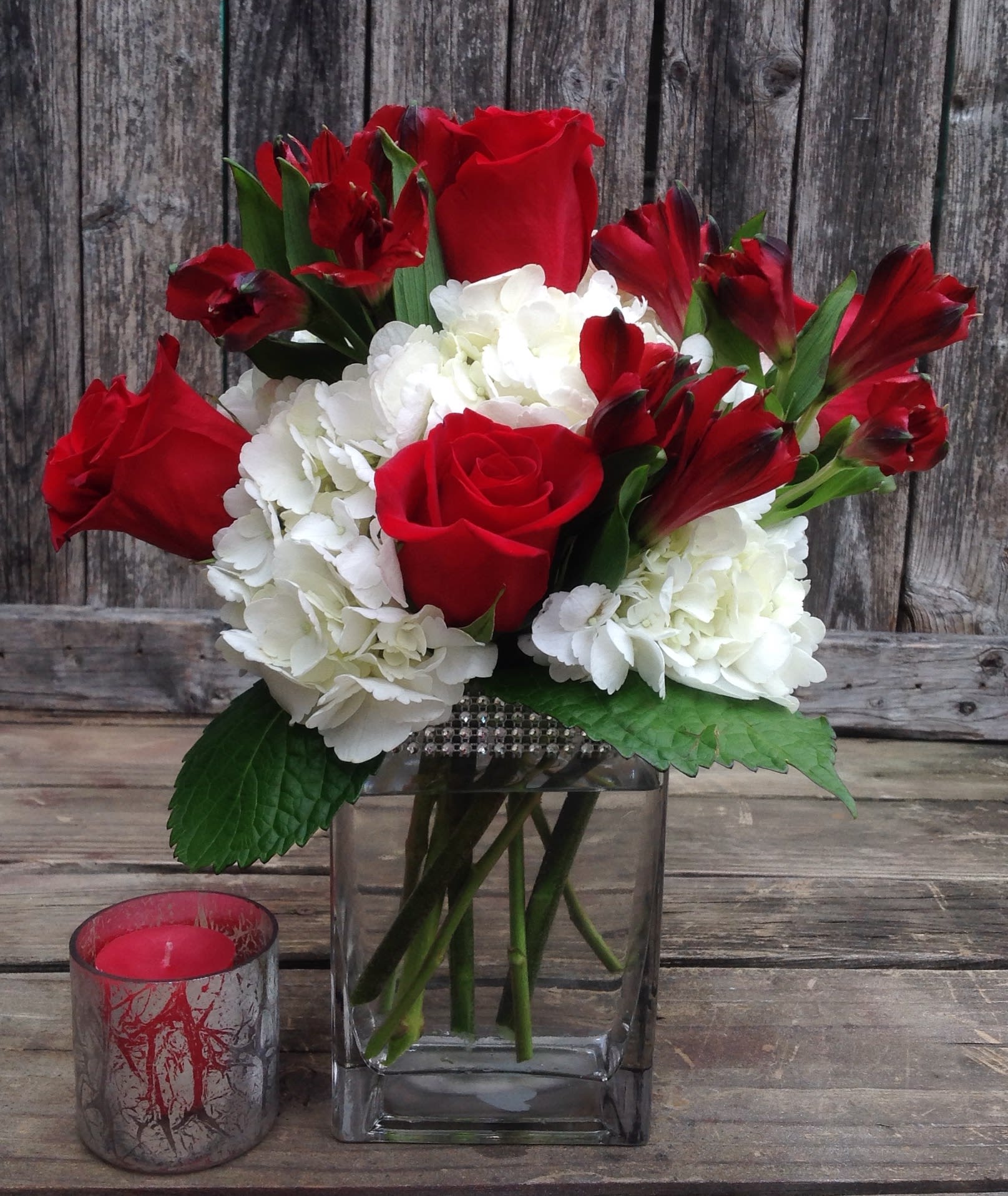 Love and Romance - Sing her a love song - with flowers. This lush, loving rose arrangement tells her just how much you care.  Contemporary vase with hydrangeas, roses &amp; red alstromerias will make her day. 
