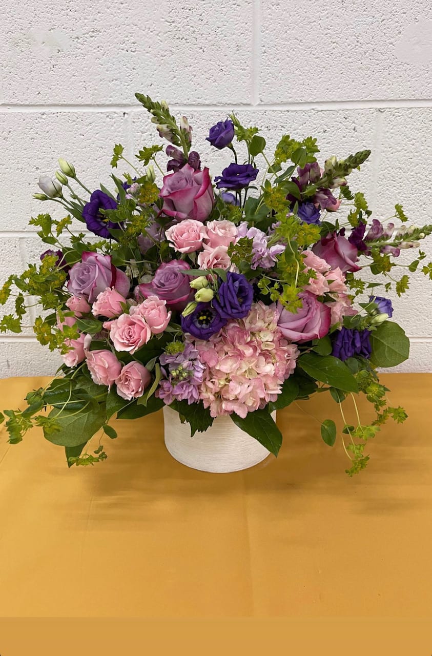 Sara's Smile Sara's Smile - The Sara's smile with certainly make your recipient smile! The lush bouquet features pink, lilac, purple and green hues in a bountiful display containing spray roses, Hydrangea, Stock, Lisianthus, Snapdragons and more in our signature white ceramic vase.