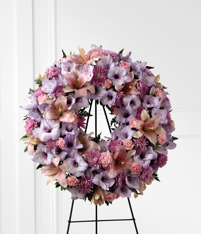 Sleep in Peace Wreath - Sleep in Peace Wreath is a soft expression of sympathy  that will bring comfort and offer hope during the final farewell.  Lavender gladiolus, pink Asiatic lilies, lavender chrysanthemums, pink  mini carnations and lush greens are beautifully arranged in the form of a  wreath for a sweet and colorful look. Displayed on a wire easel, this  wreath is a lovely way to honor the life of the deceased.    