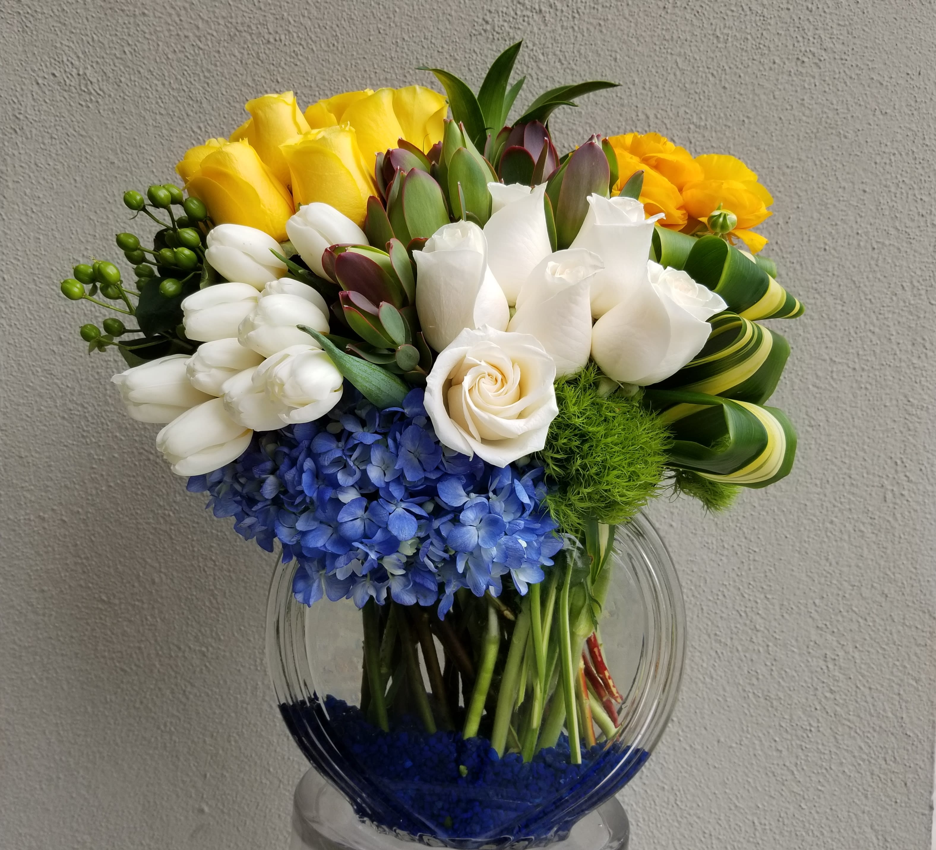 Sunrise - Flat bowl composed of white, blue and yellow blooms such as roses, tulips, hydrangeas, and ranunculus.