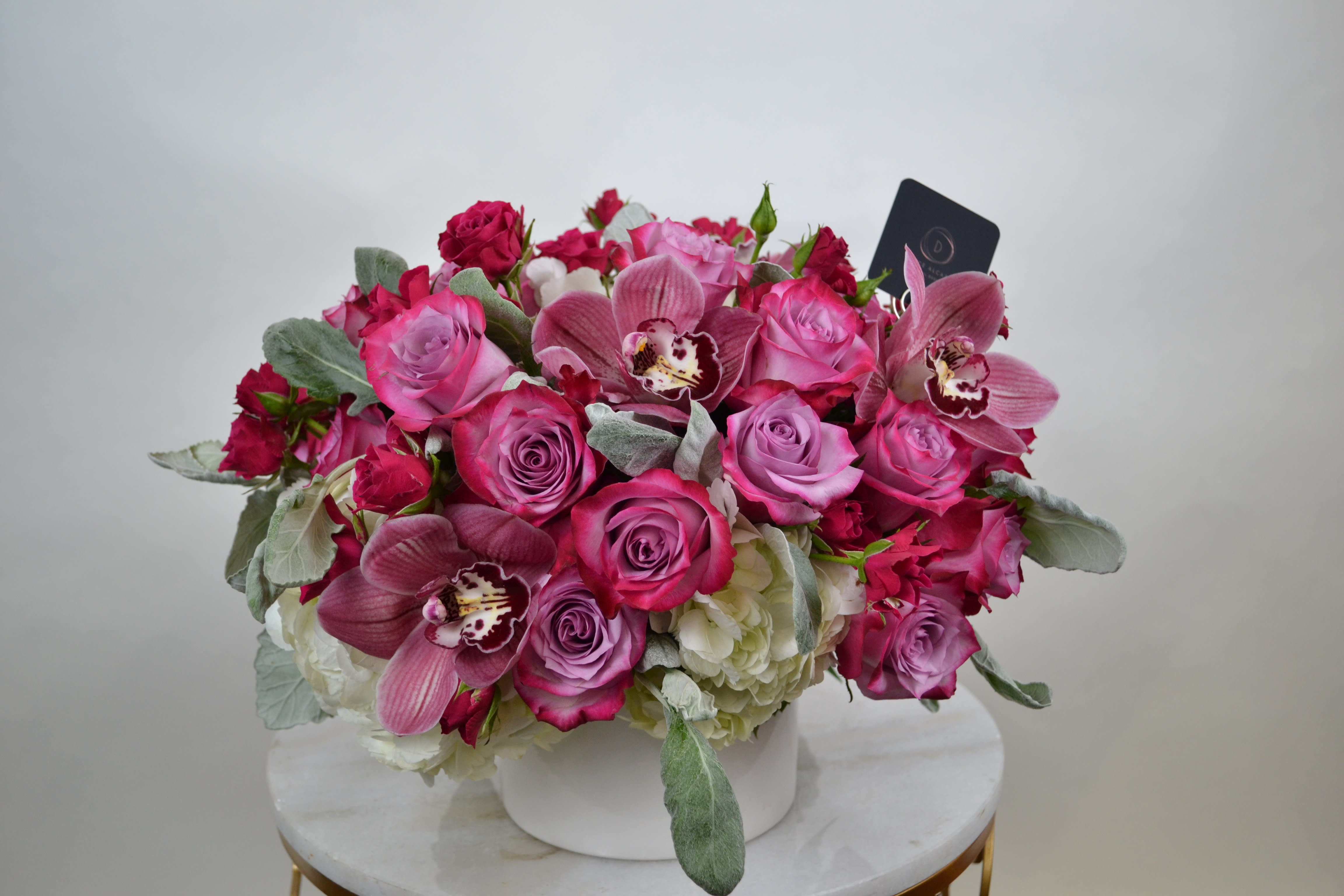 ROSE PRICK - White base  with a layer of hydrangea white, dusty miller, spray rose, roses and  an exquisite  touch of cymbidium! 