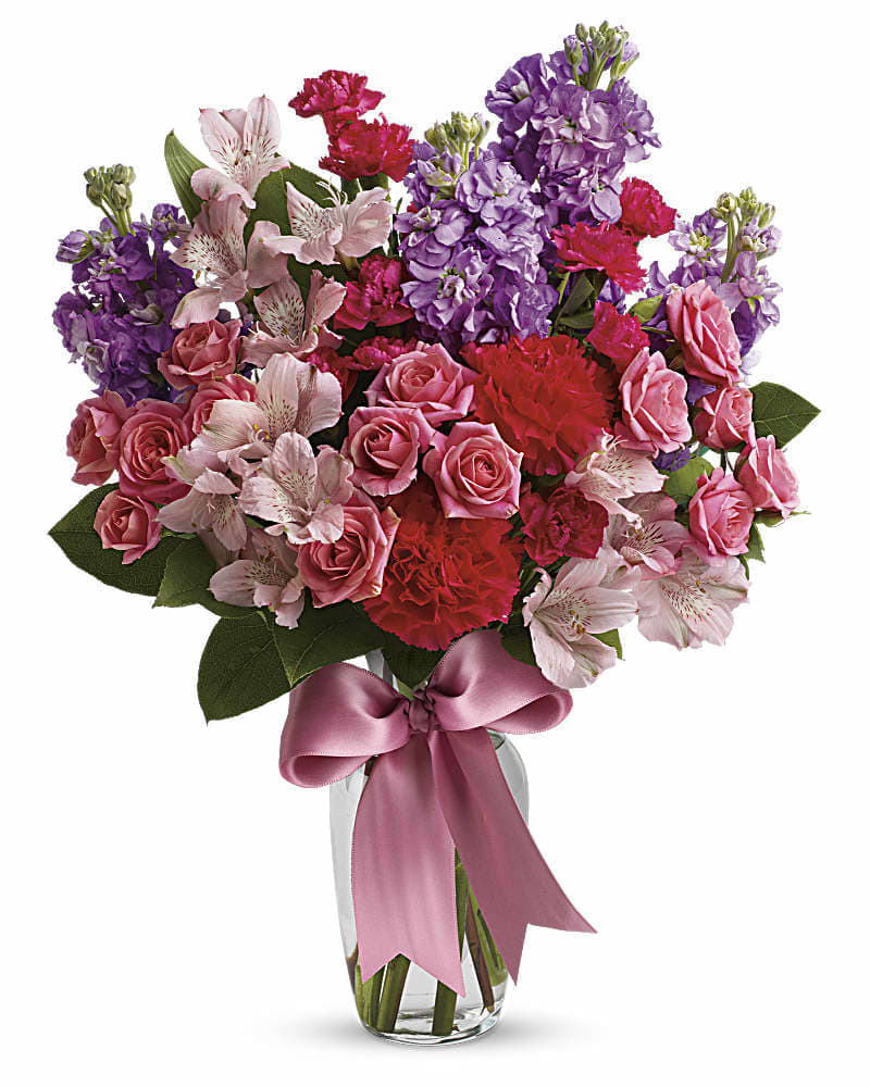 Jumping for Joy - Send her on a dreamy stroll through a garden with this perfect-for-any-occasion bouquet. Soft lavender and pink flowers delight with a sweet smell; a pink ribbon adds to the feminine look of this traditional arrangement. Lush lavender stock, pale pink alstroemeria, hot pink spray roses and mini carnations are delivered in a traditional glass vase adorned with a pink ribbon.