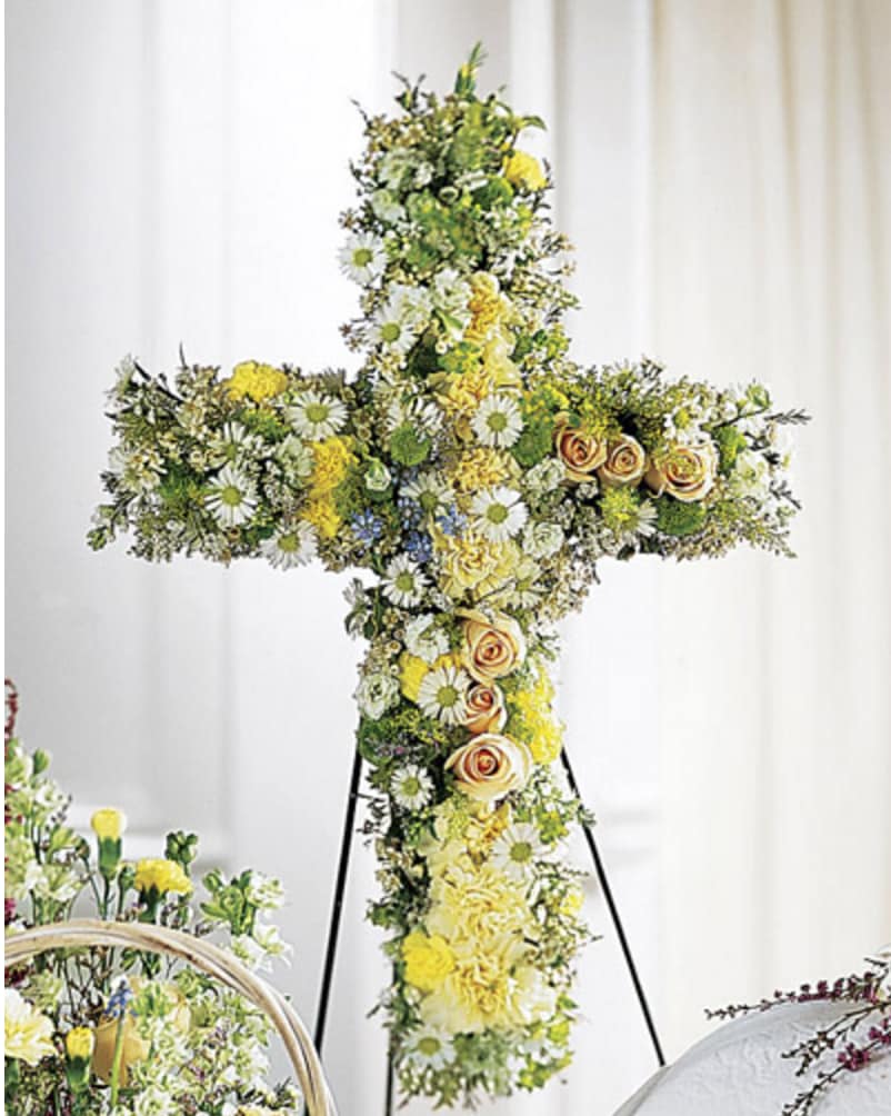 Angel's Cross Easel Angel's Cross Easel - A beautiful religious sentiment, this cross features 13 different tightly arranged flowers in peaceful, natural tones. Flowers include peach roses, cream carnations, yellow mini carnations, white monte casino and more. Delivered on an easel and appropriate to send to a funeral home or service. Standard size 30" tall form used. Deluxe size 36" tall form used.