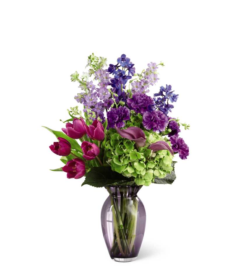 The FTD Always Remembered Bouquet - The FTD Always Remembered Bouquet is a colorful symbol of a life that will never be forgotten. Purple tulips, blue delphinium, lavender mini calla lilies, purple carnations, lavender larkspur and green hydrangea are gorgeously arranged in a clear purple designer glass vase to create an emotional tribute that conveys your deepest sympathies.