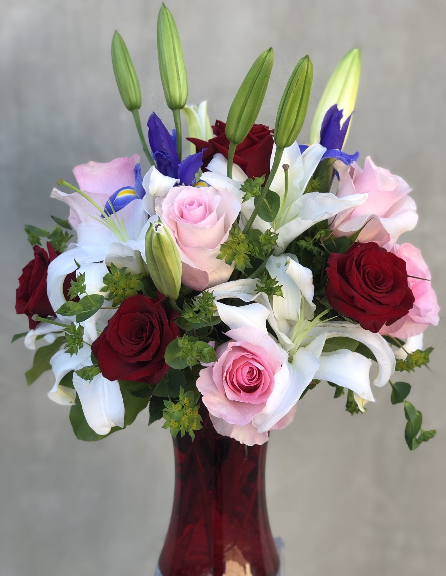 Pink Love - Classic arrangement filled with pink and red roses, with a touch of white lilies and iris arranged in a tall vase. 