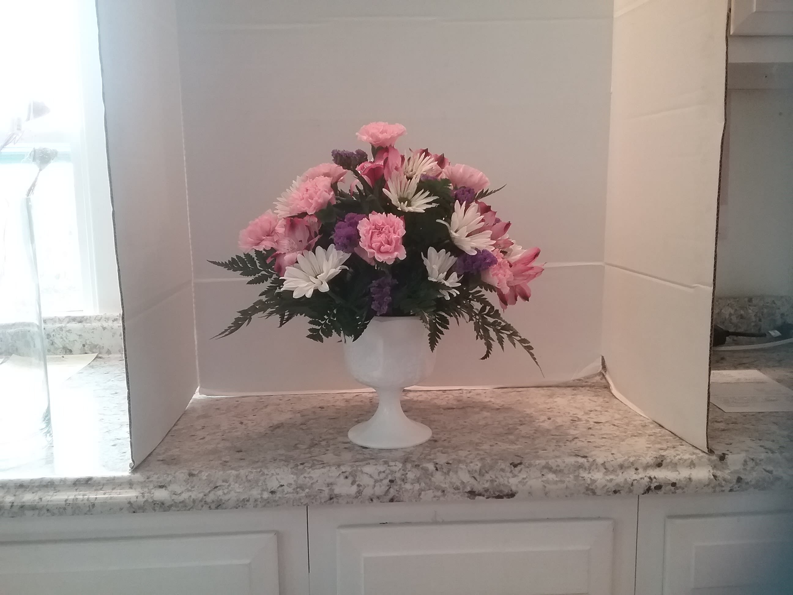 Pink elegance - Pink carnations and pink alstromeria, daisies and status arranged in a milk glass container make this a unique gift.