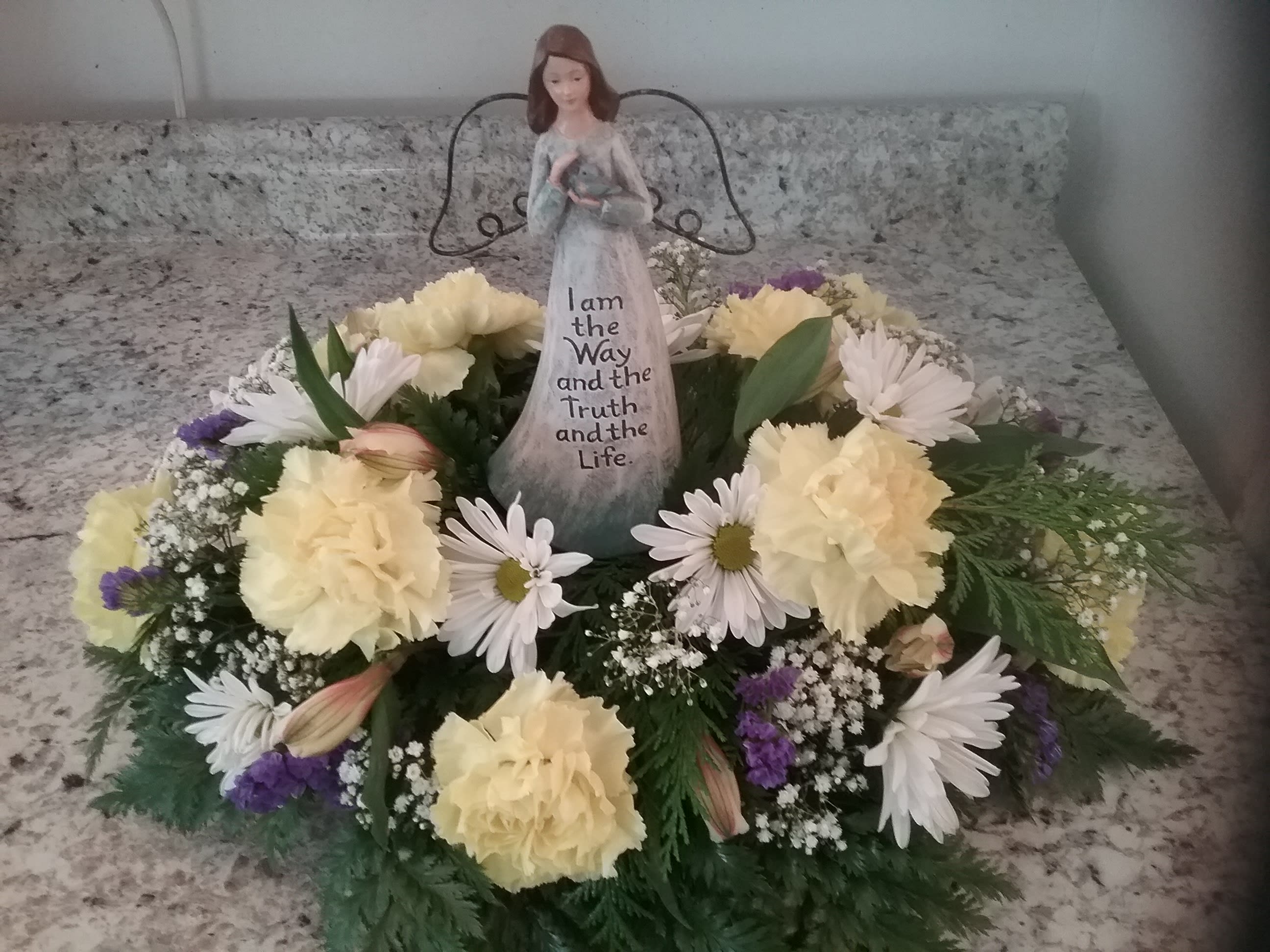 Centerpiece with Angel  - Carnations, and daisy's are not the center attraction in this little centerpiece.  This little angle is a little surprise for every occasion.