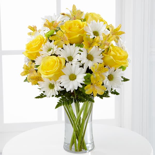 The FTD Sunny Sentiments Bouquet - The FTD® Sunny Sentiments™ Bouquet is a blooming expression of charming cheer. Brilliant yellow roses and Peruvian Lilies are paired with white traditional daisies and green button poms to create a memorable bouquet. Accented with lush greens and arranged in a classic clear glass vase this bouquet is a wonderful way to celebrate any of life's special moments