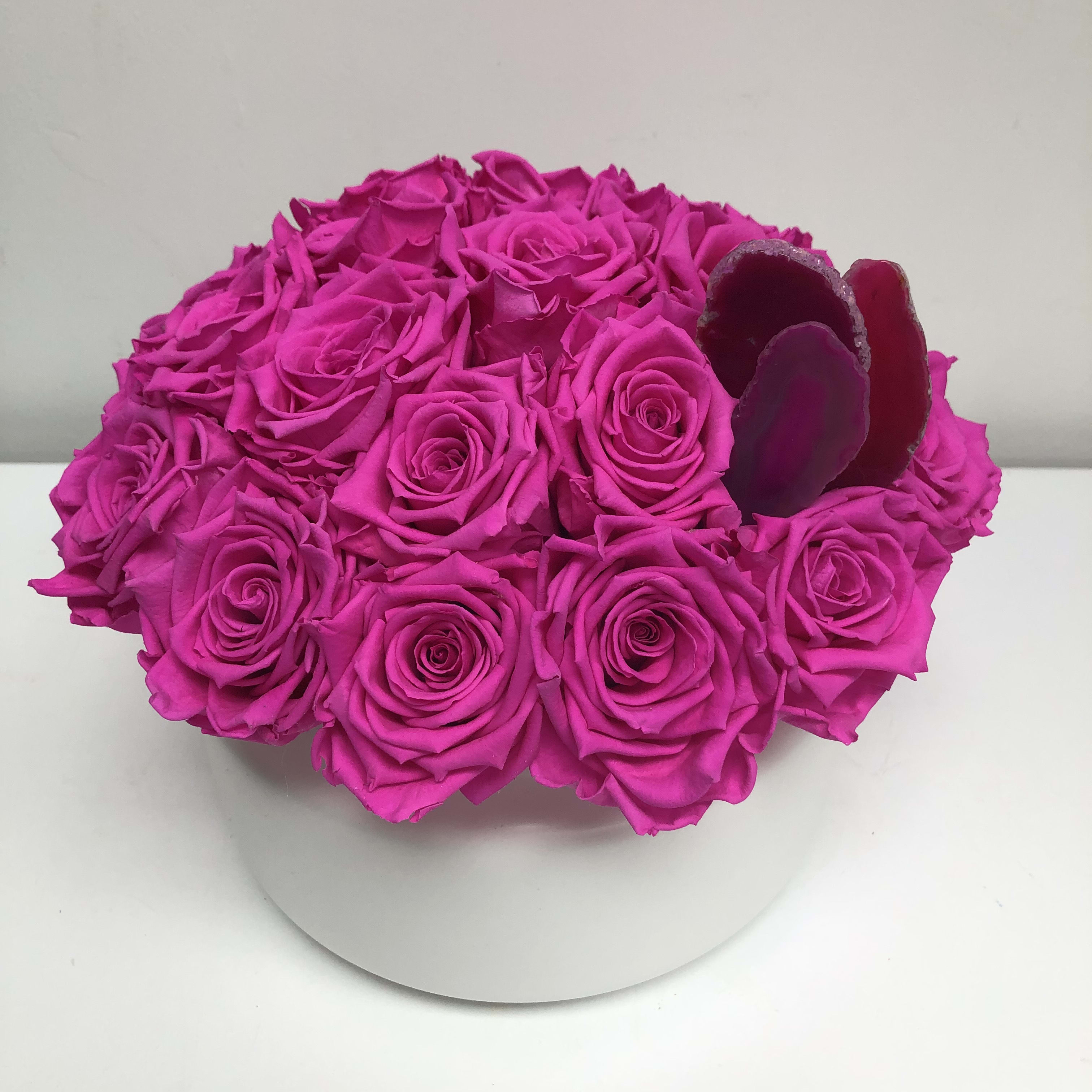 Pink Preserved Roses in White Glass Pink Preserved Roses in White Glass - An arrangement of long lasting preserved roses in white glass vase. Measures 10” wide by 8” high.