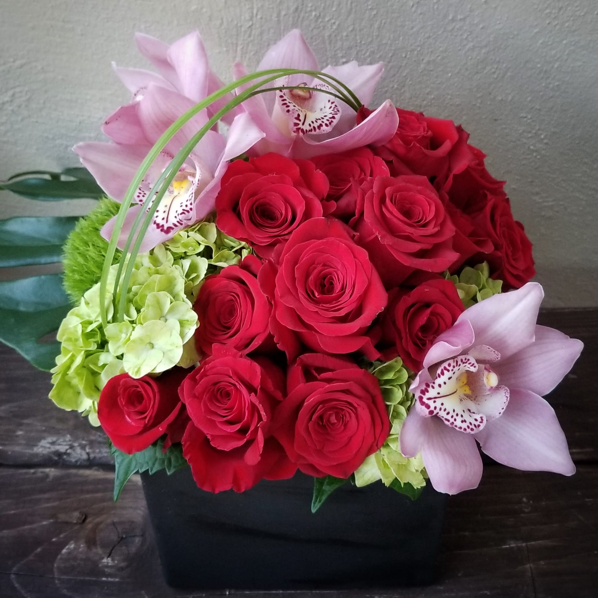 Roses &amp; Orchids - What a combination of amazing flowers this is. 'Roses &amp; Orchids' is one of those classic combinations of blooms when you are wanting something really special. The Rose, in and of itself, has for centuries been one of the most favorite flowers people love. Between the colors of the delicate petals and fragrance, roses have been a very traditional gift when you want to tell someone you love them. The other bloom featured in this design is the Orchid has its own spectrum of special qualities. Orchids have always been a very sought-after bloom. Collectors of Orchids have coveted these rare gems for centuries. For that reason, Orchids have always been associated with wealth and good fortune. They have been loved for their longevity, exquisite colors, and exotic form. Put these two extraordinary blooms together in one amazing flower bouquet... &quot;Bellissima&quot;!  When we create this beautiful bouquet it is always quite the occasion. All of the special qualities of these flowers mingle with beautiful foliages in a stylish modern vase. This is one flower bouquet that knows how to make an entrance. So, if you are ready to make someone's day extraordinary, let's make it happen!
