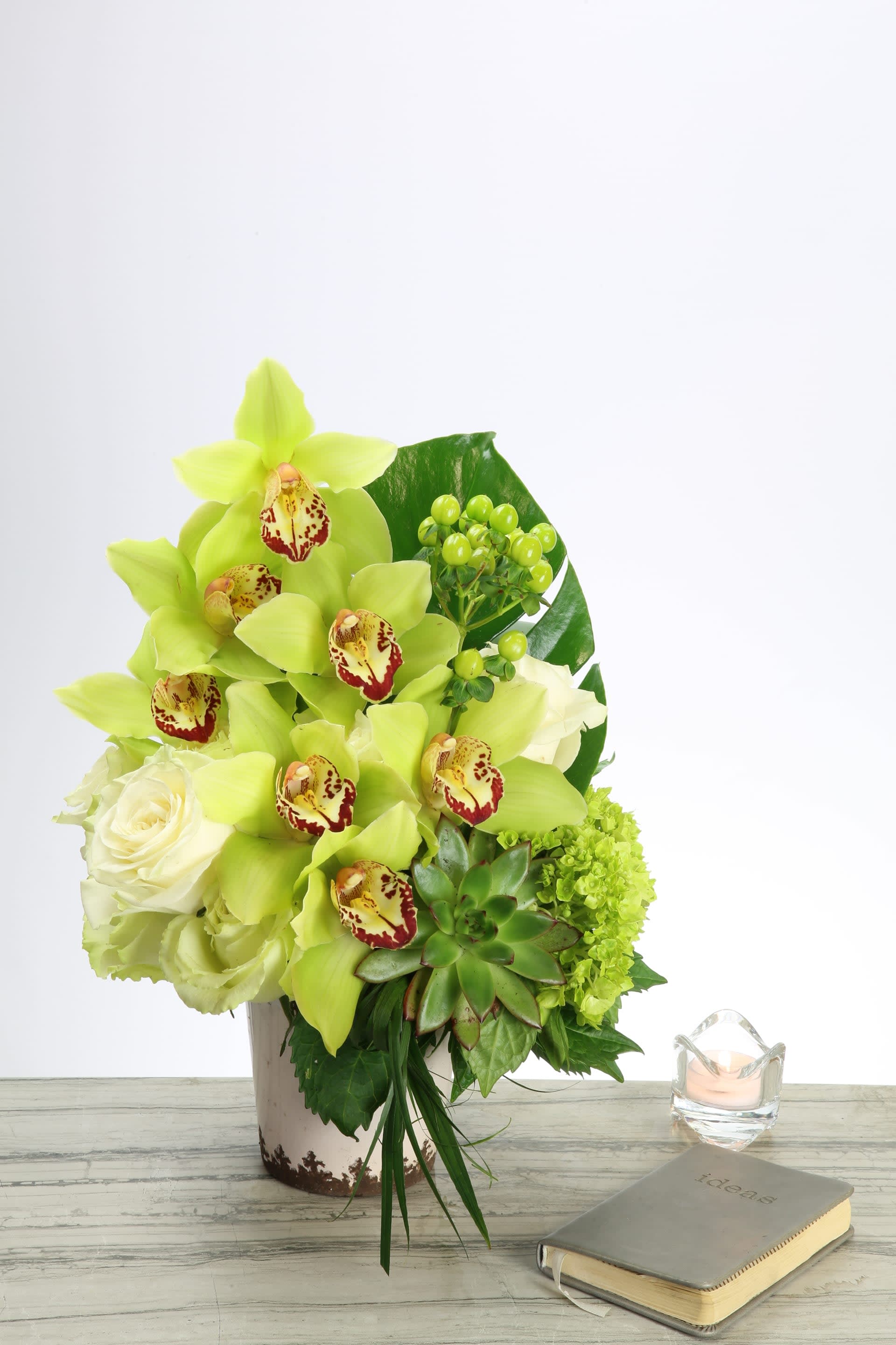 Honeydew Heaven Honeydew Heaven - Classy and elegant .... Imported Green Orchids are arranged in a pyramid shape in a ceramic pot with lovely touches of White South American Roses, succulents, green Hydrangeas, berries, and large leafy greens. These stunning shades of greens and white compliment each other beautifully in this harmonious design.