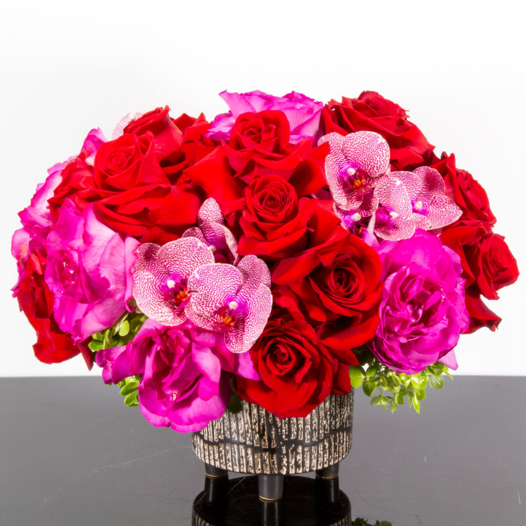 The Color of Paradise - Gorgeous reflex Garden Roses and Phalaenopsis orchids fill this weathered wooden pedestaled container with freshness. Whether you're saying thank you to a special friend or sharing the most heartfelt get-well message, this arrangement is a breathtaking gift for your loved ones to cherish.