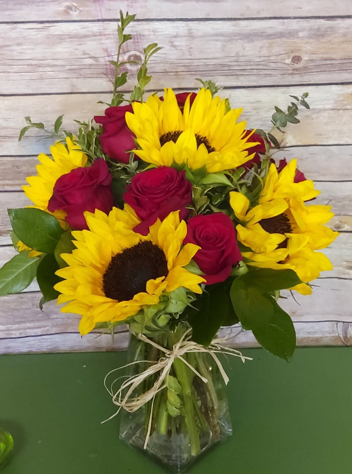 Sunflowers in Love - Red roses mean love and romance. Introduce the enamored red rose to the bright and ever vibrantly eye catching sunflower and fiery magic happens in a curvy old fashioned vase. This is for that burning love.