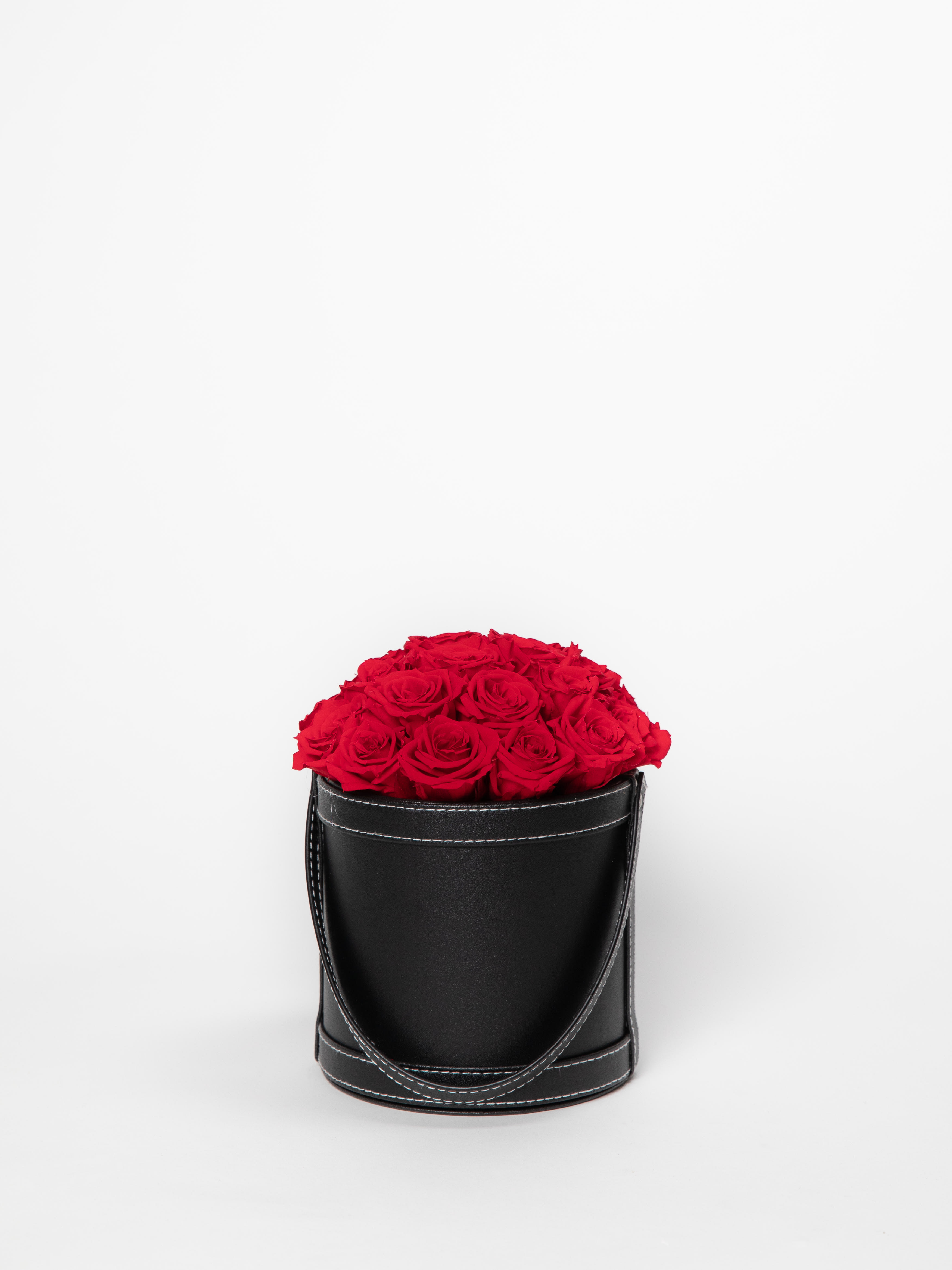 Small vegan leather box with medium red roses - This timeless arrangement is a part of our Everlasting Collection and features real flowers that last up to three years. Set in our hand-stitched vegan leather round box.   Our freshly picked Everlasting flowers have been chosen by expert farmers, and have gone through a technological process that enables them to become preserved. These flowers look and feel precisely like freshly cut flowers, but can last up to 3 years in the right conditions! Once our talented florists receive these flowers, they are arranged and designed inside a beautiful hand-stitched box. Everlasting flowers are the perfect choice for you to decorate your home or pamper your loved ones on special occasions.   Caring for Everlasting flowers:  1. Do not water the arrangement. 2. Keep the arrangement indoors. 3. Keep the arrangement out of direct sunlight. 4. Keep the arrangement in a cool, dry place. 5. Do not crush, press, or fold the petals.  **Please note that variations will occur since all of our arrangements are handmade by our in-house designers.** 