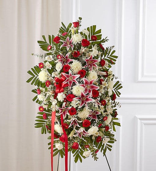 Red Rose and Lily Standing Spray - Celebrate a life well lived like a true, rare treasure. Our sophisticated and elegant standing sympathy spray is arranged with rich and radiant ruby red roses and Matsumoto asters, Stargazer lilies, white carnations and mums. A resplendent tribute to a loved one that will express your deepest sympathies.