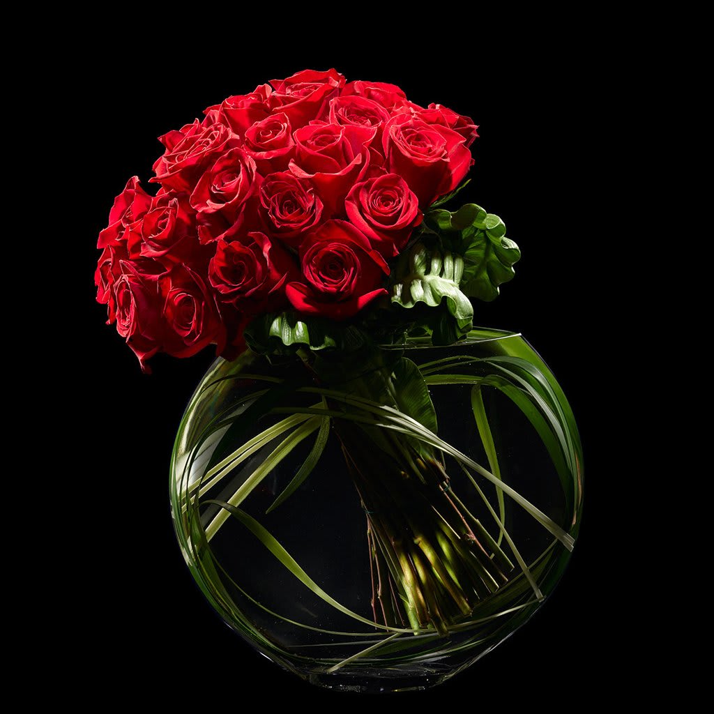Seduction Seduction - Beautiful Contemporary design 24 Red roses hand tied and presented in our signature glass crescent bowl. Grass loops spiraled inside the vase give the finishing touch to this 'Seductive' design! 36 rose option available Other colors of roses - Pink, Yellow, White