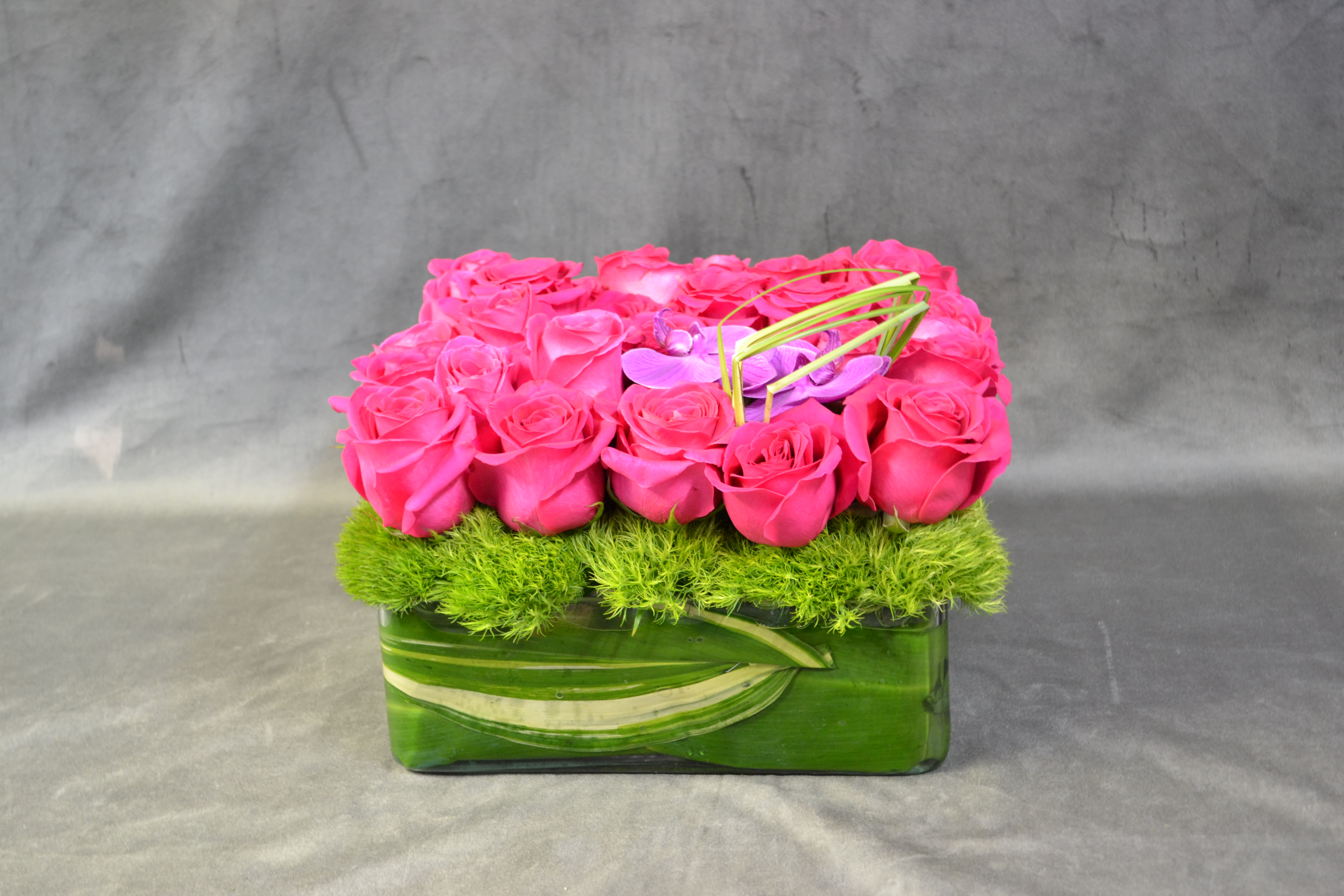 Hot Pink - Hot pink roses and phalaenopsis orchids beautifully decorated with greens.